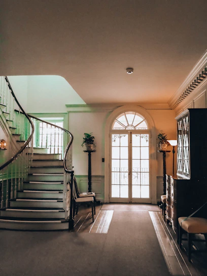 Elegant hallway with a grand staircase and arched doorway.