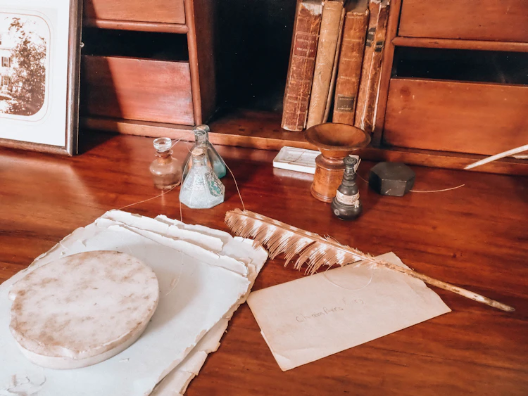 An antique wooden desk with a quill pen and old papers