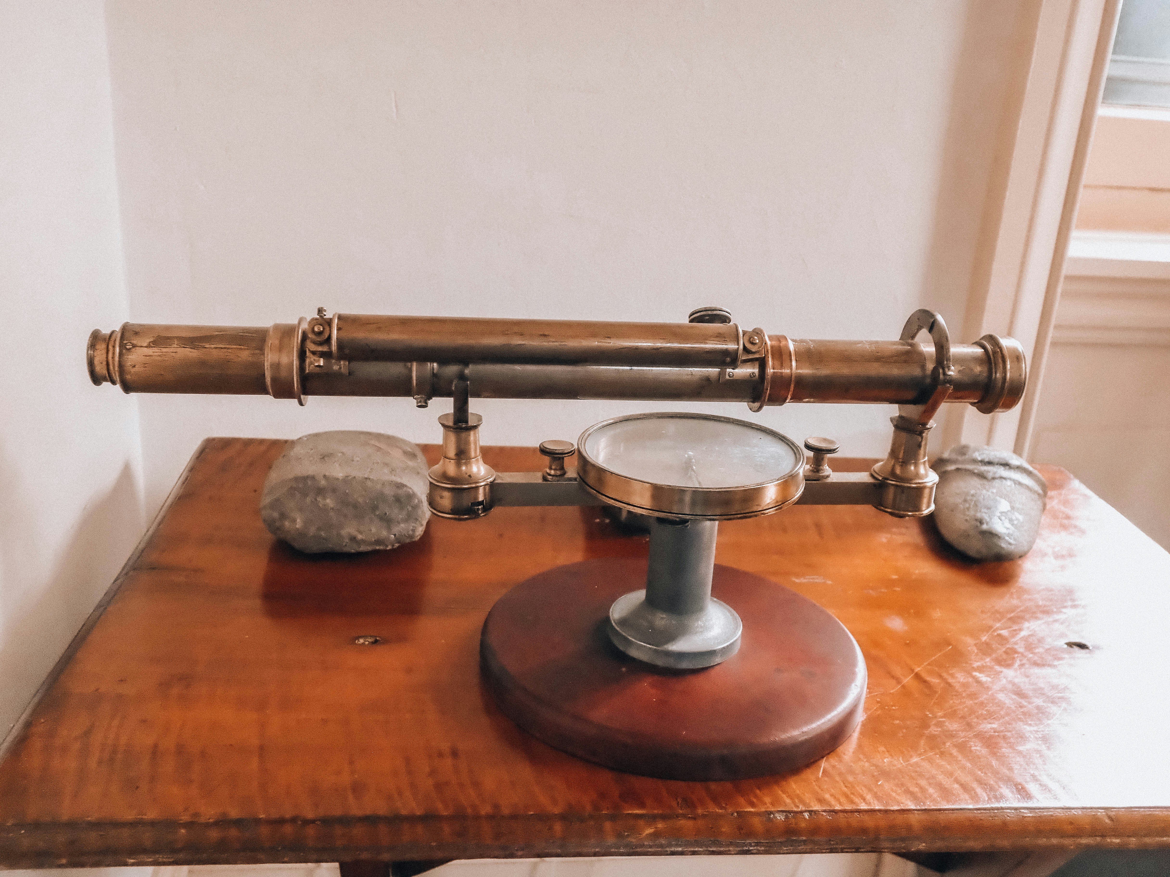 Antique brass surveying instrument on a polished wooden table.