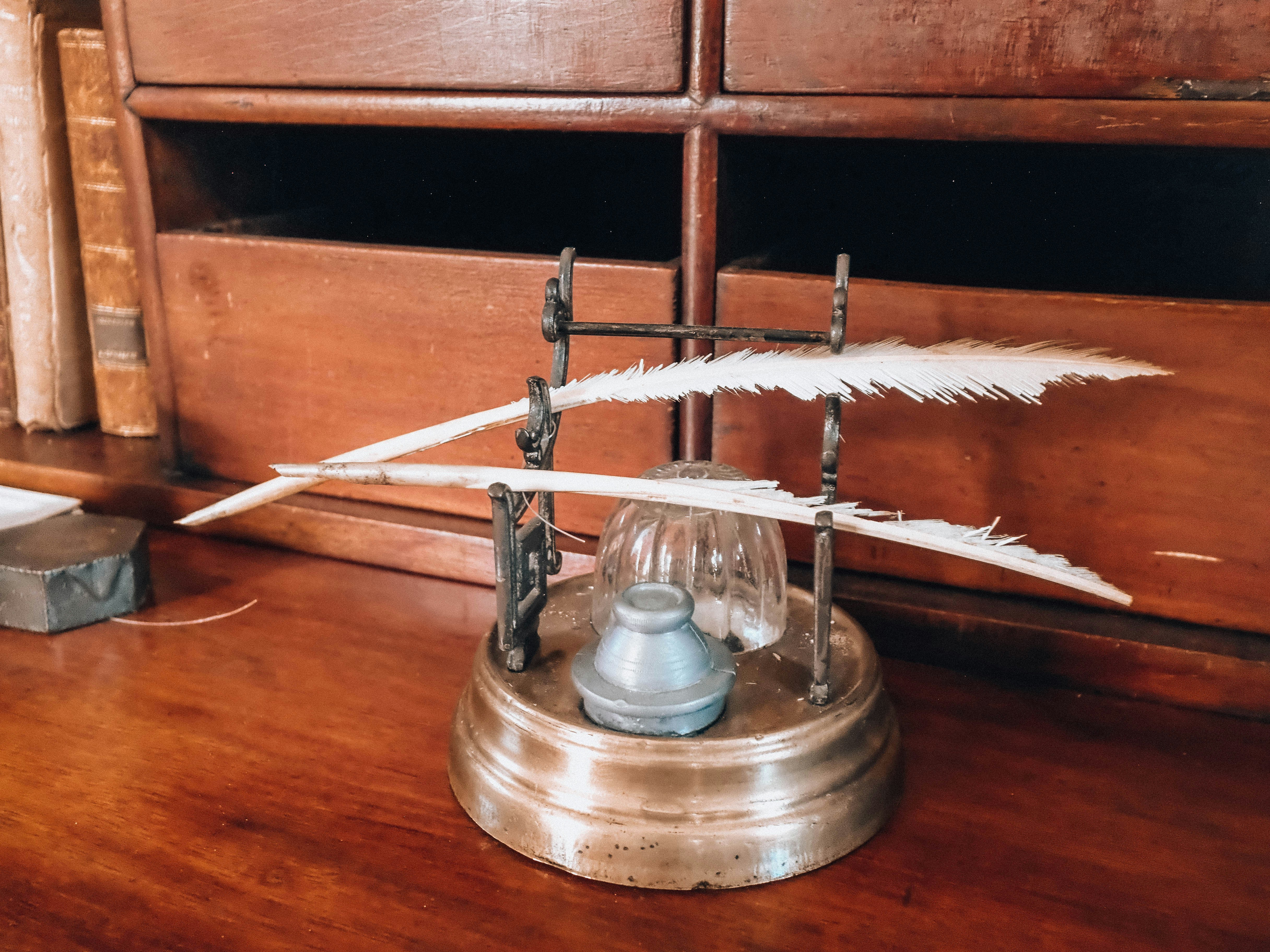 Quill pens and inkwell on a vintage wooden desk.
