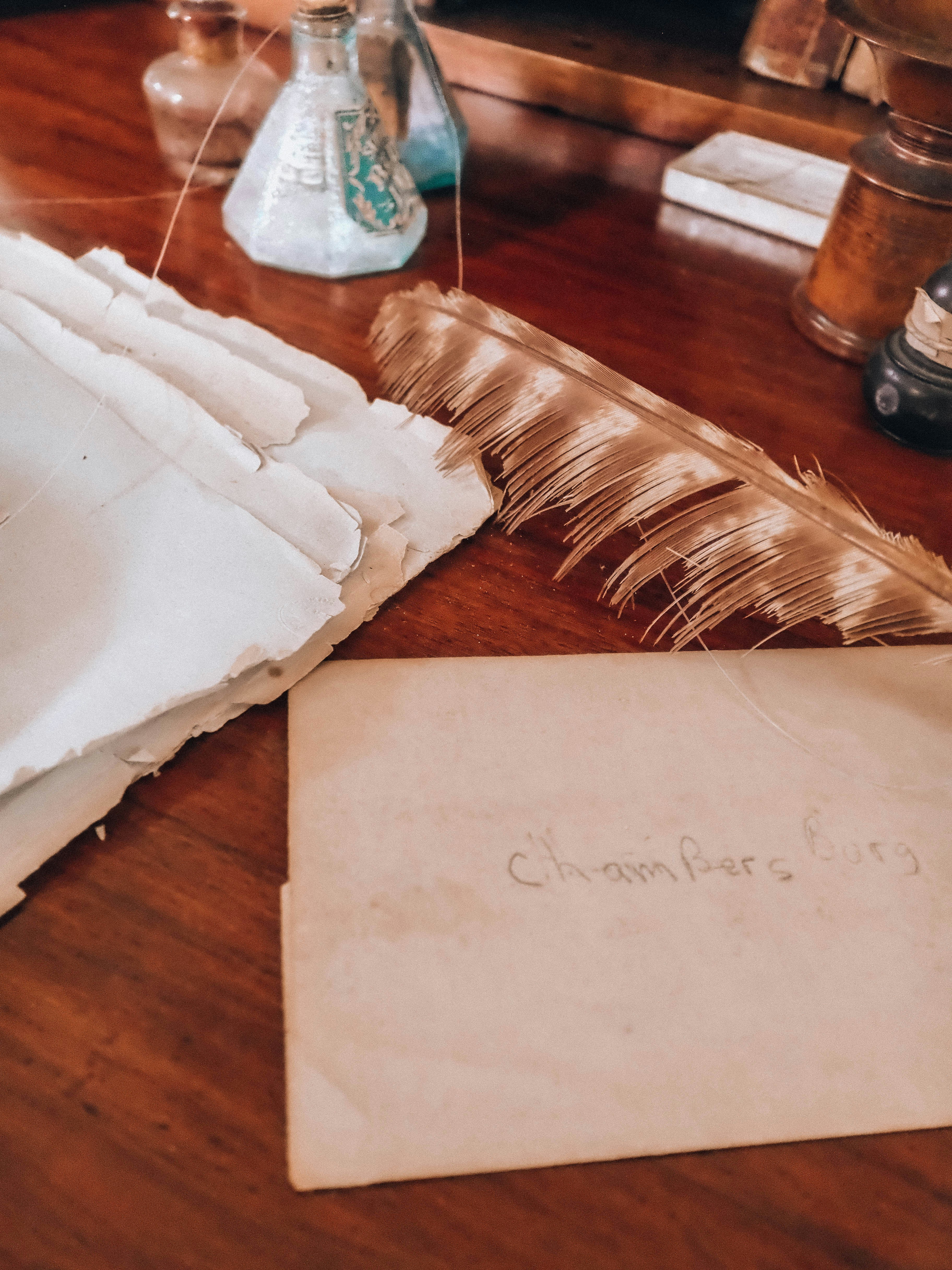Vintage writing desk with paper, quill, and inkwells.