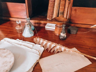 Antique writing desk with old books, ink, quill, and paper.