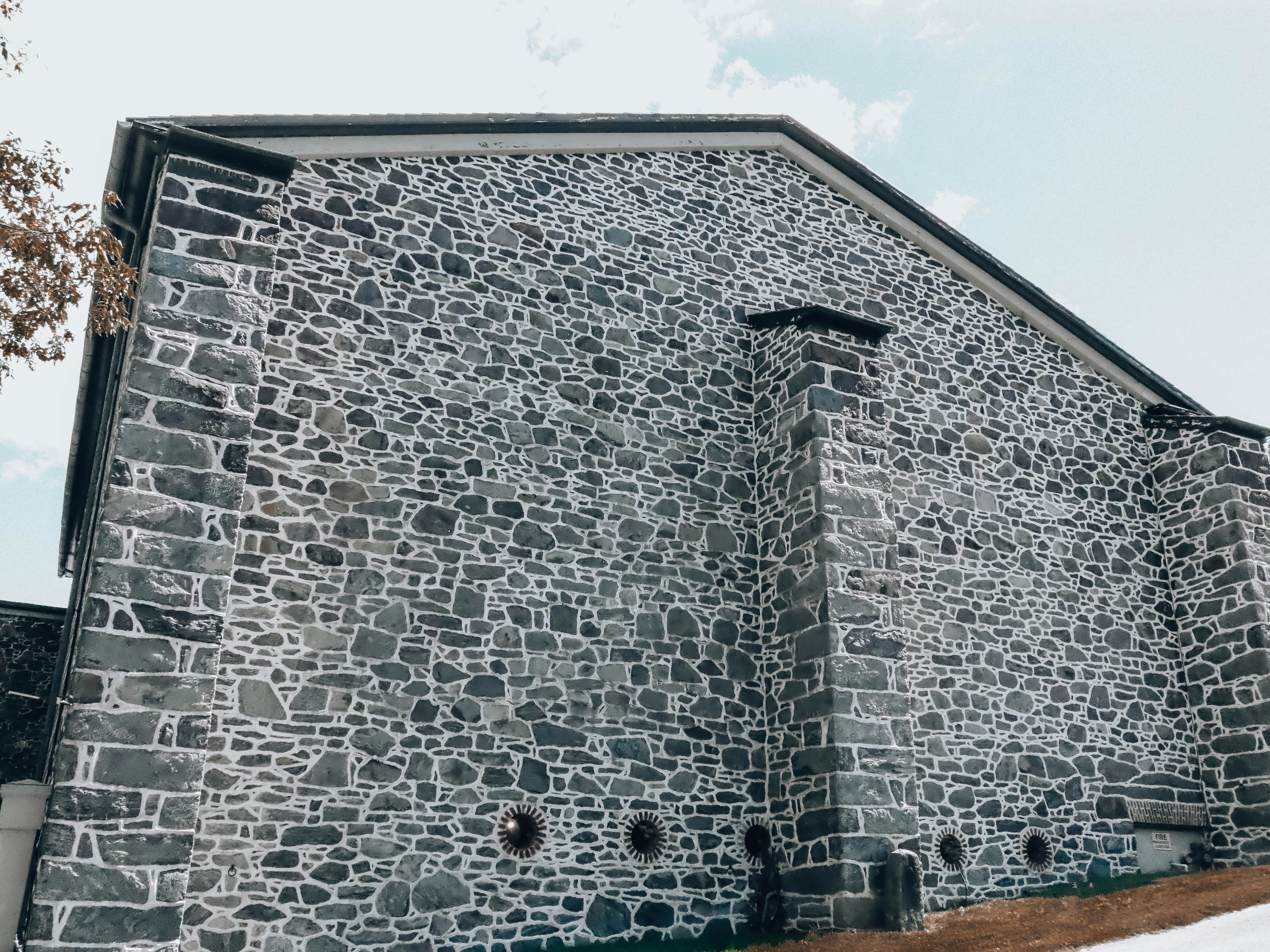 Bâtiment historique en pierre avec cheminée et petites fenêtres rondes.