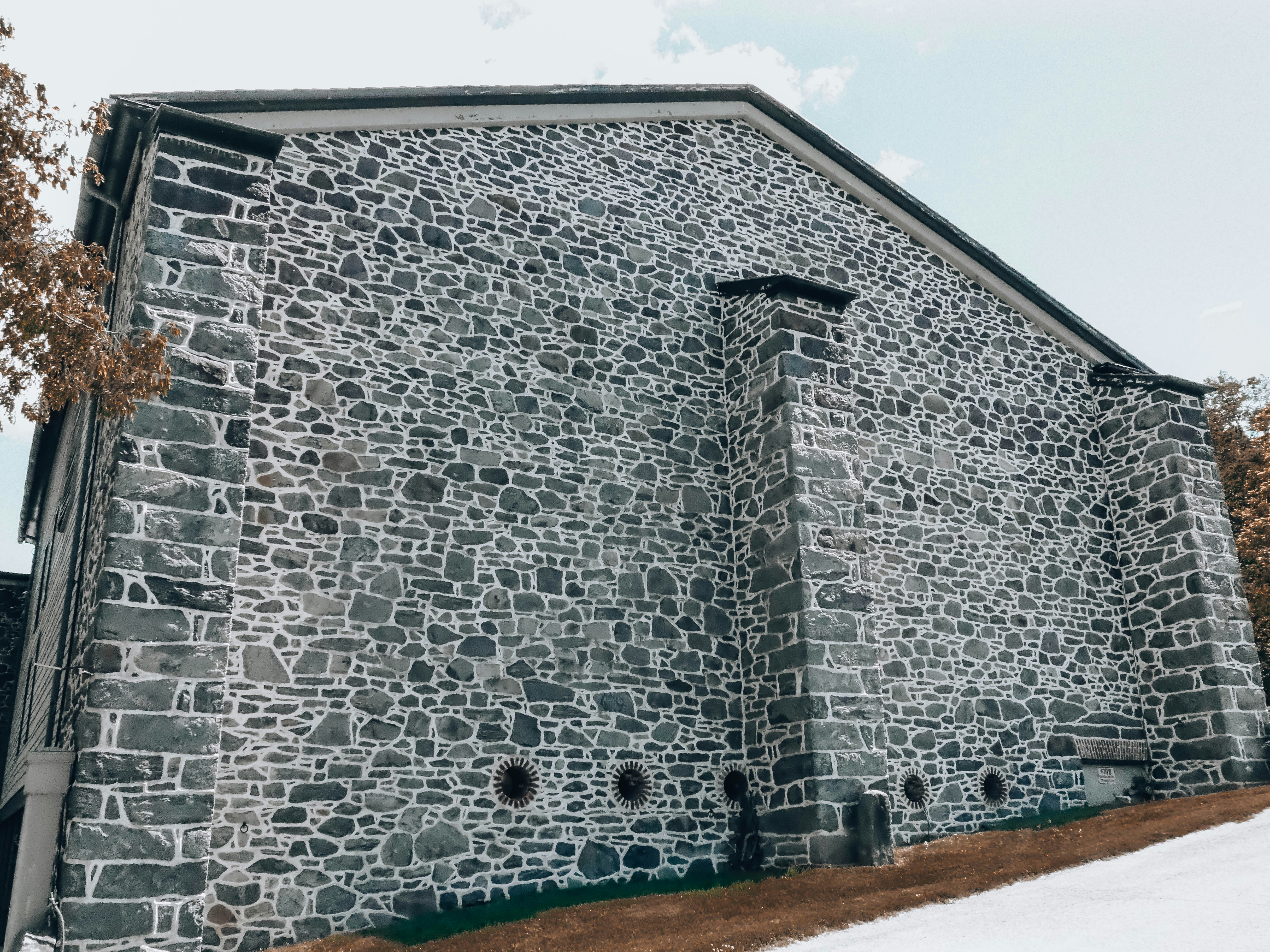 Grand bâtiment en pierre avec cheminée sur une pente enneigée.