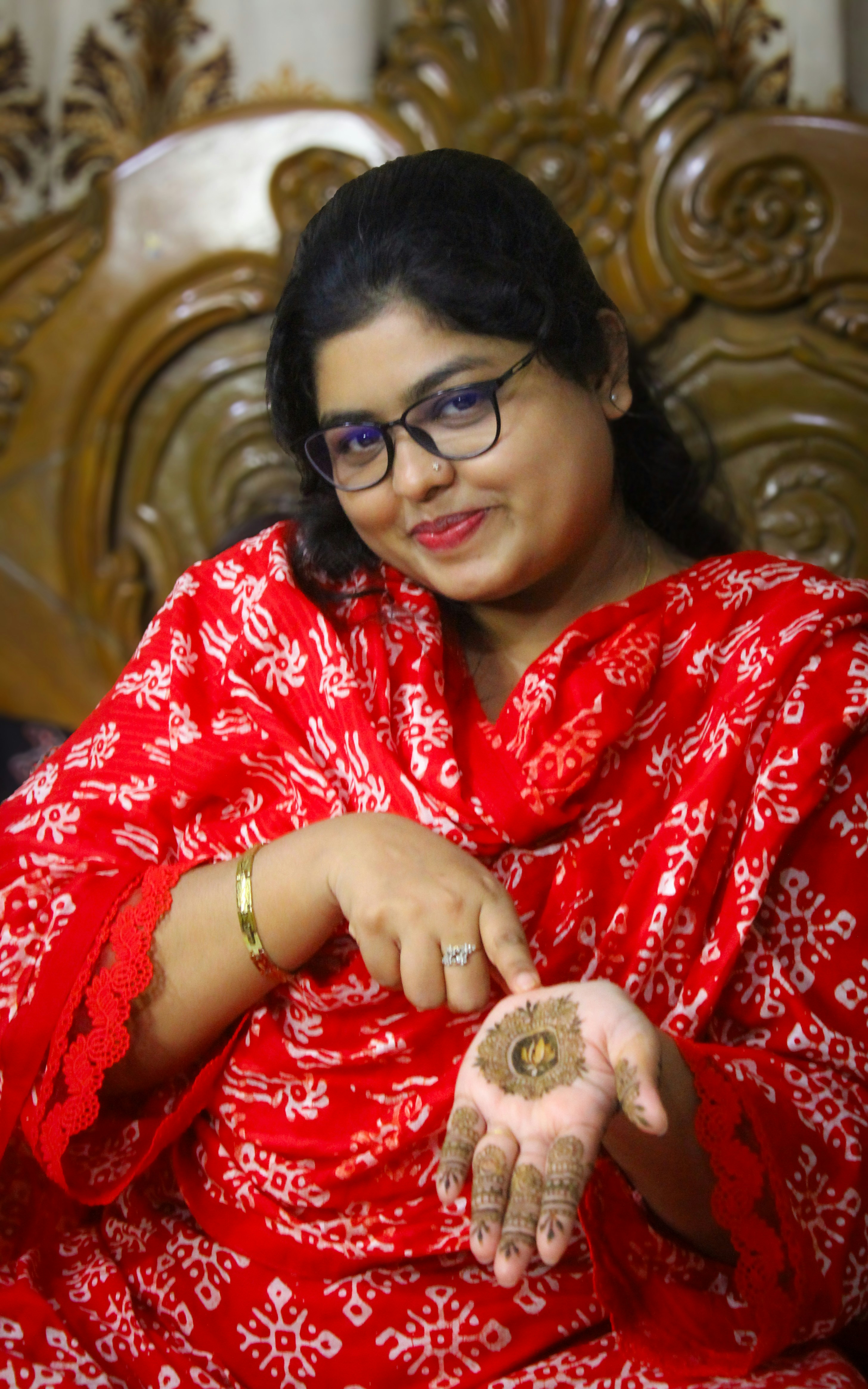 Wanita tersenyum berbaju merah menampilkan pasta henna di telapak tangannya.
