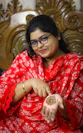 Smiling woman in red displays henna paste on her palm.