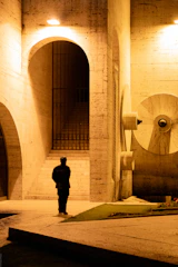 Guard stands in an arched concrete building at night