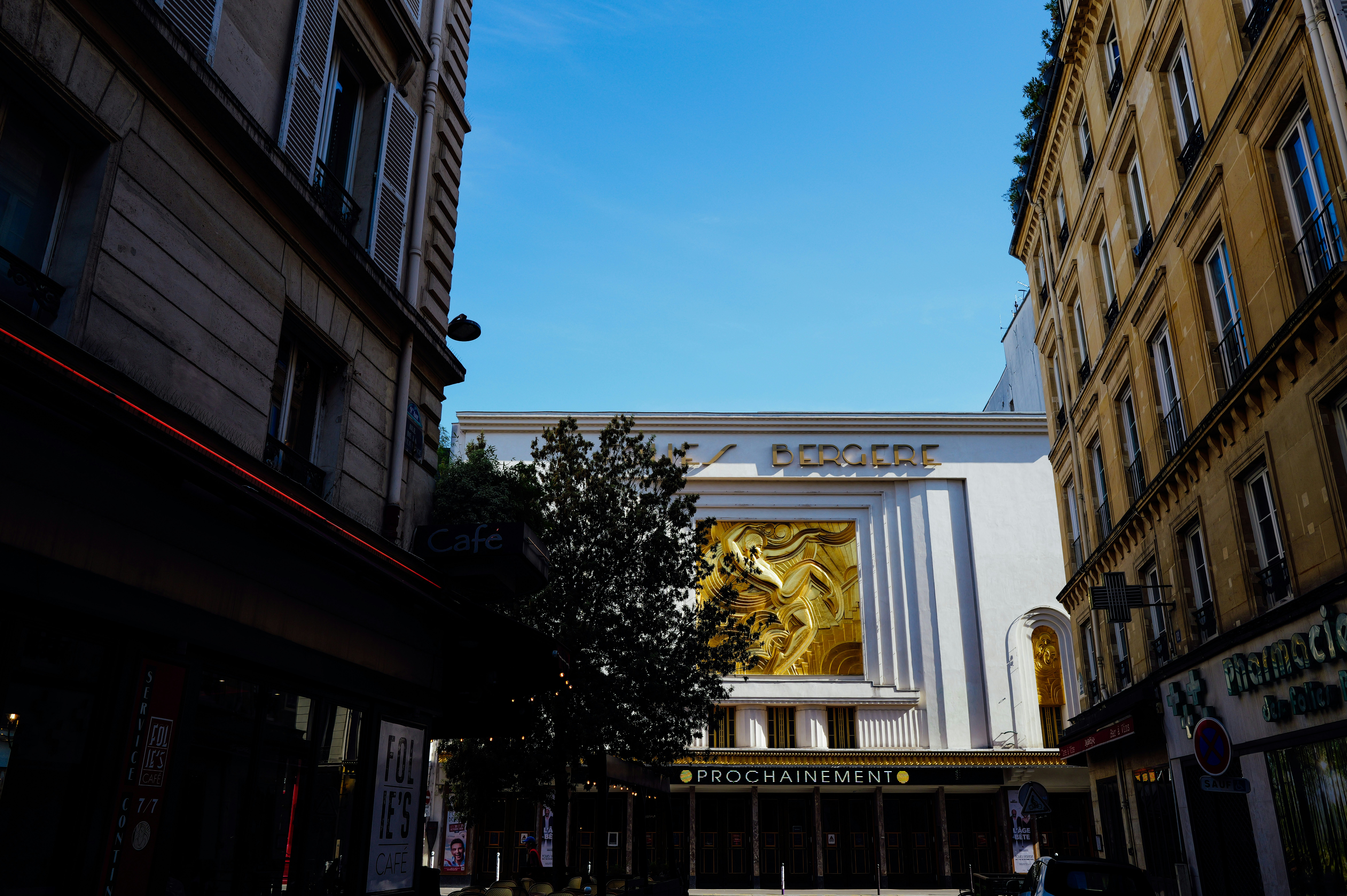 Ornate golden cinema facade framed by narrow city buildings.