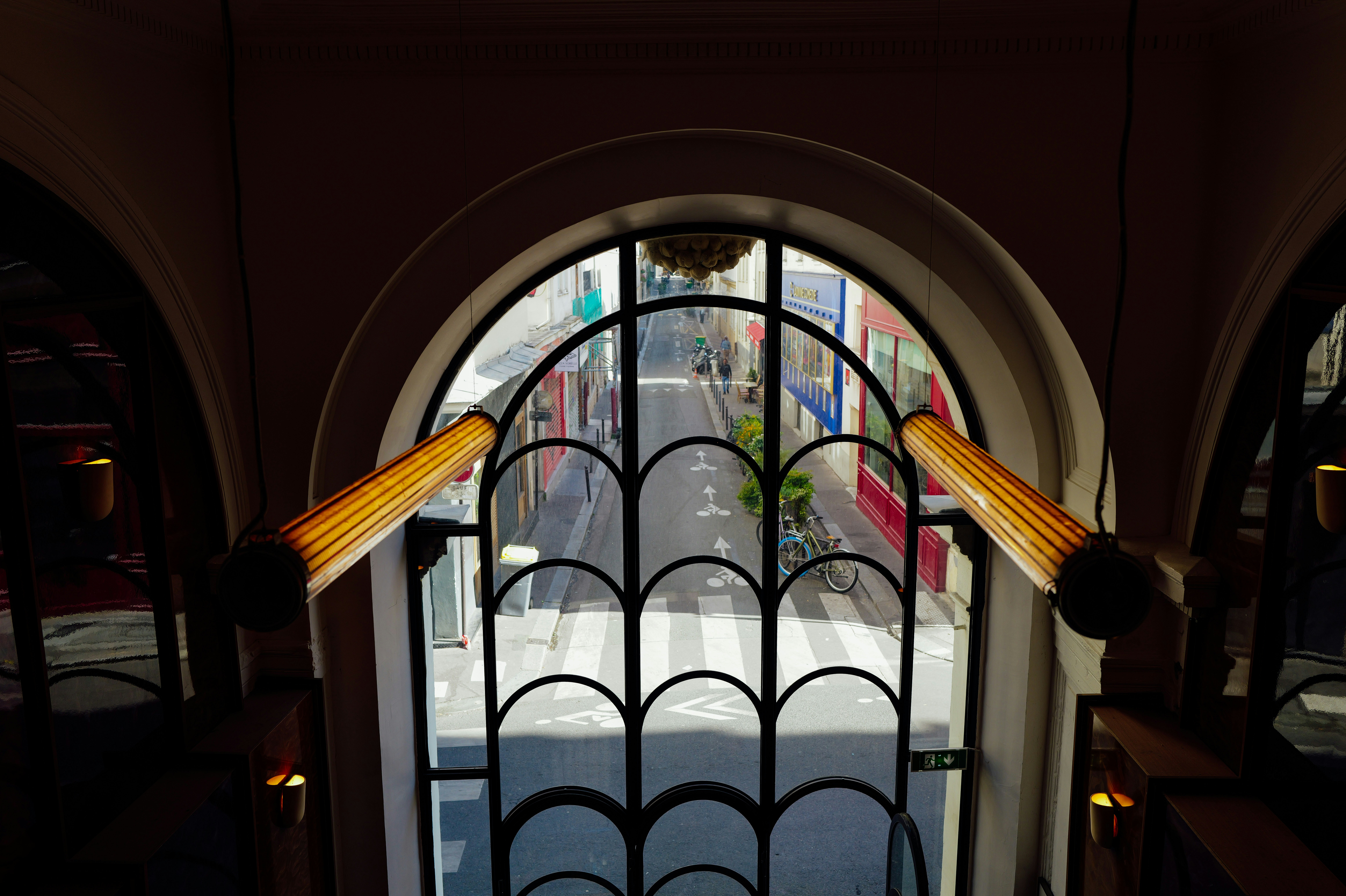 An arched window with decorative elements overlooking a street.