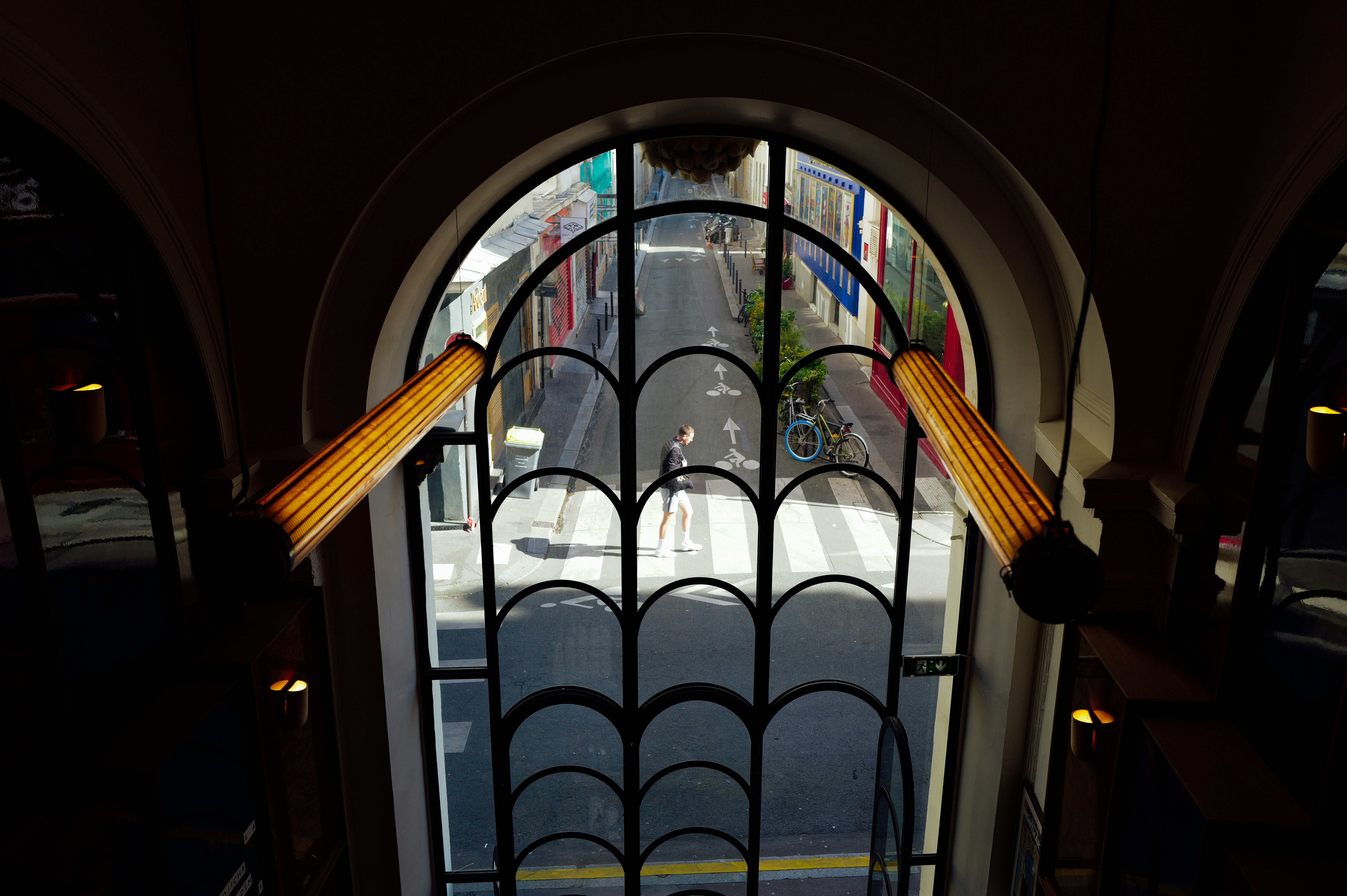 Ornate arched window frames a vibrant street scene below.