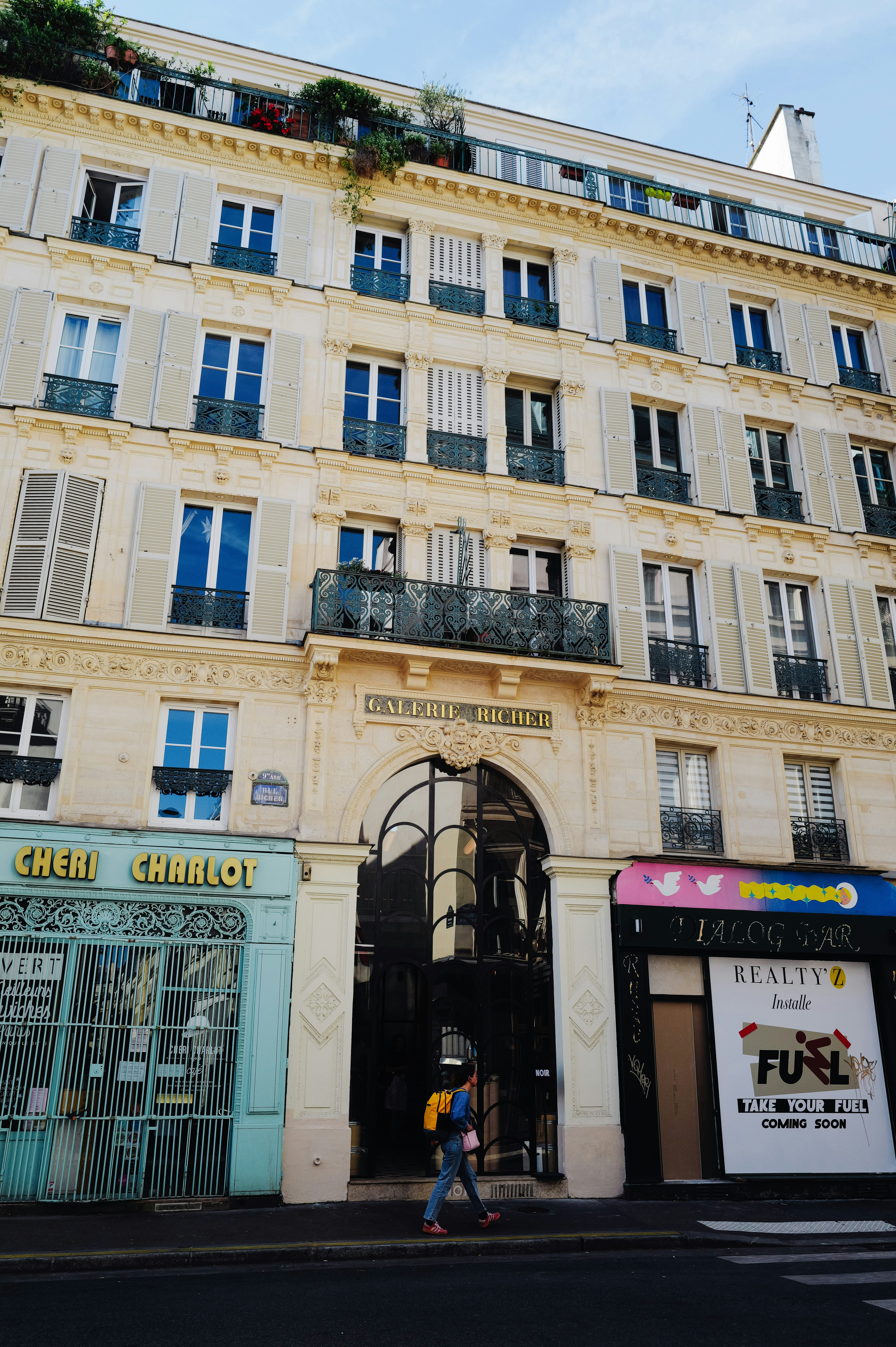 Historic parisian building with shops and a walking person.