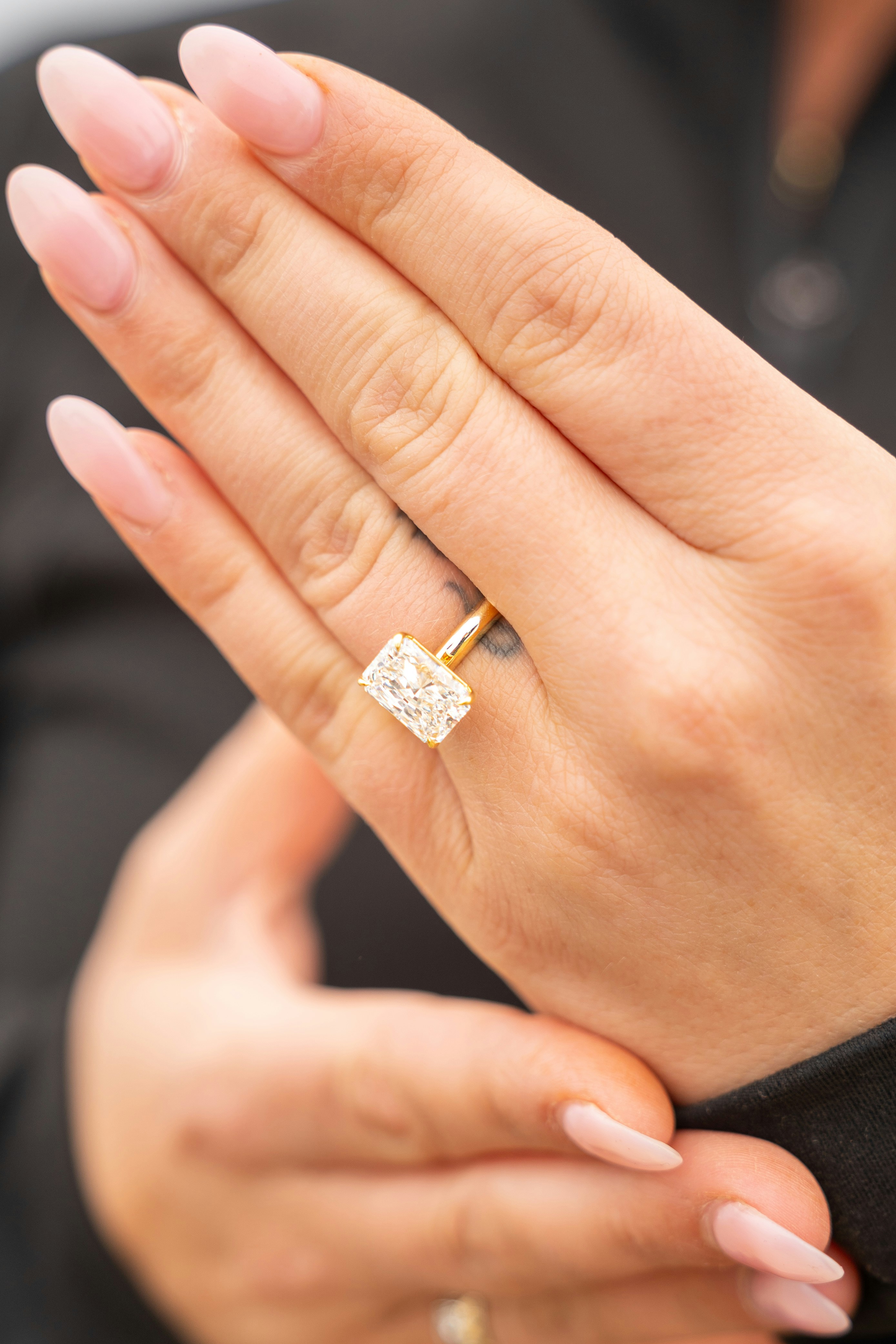 La mano di una donna mostra un grande anello rettangolare di diamanti.