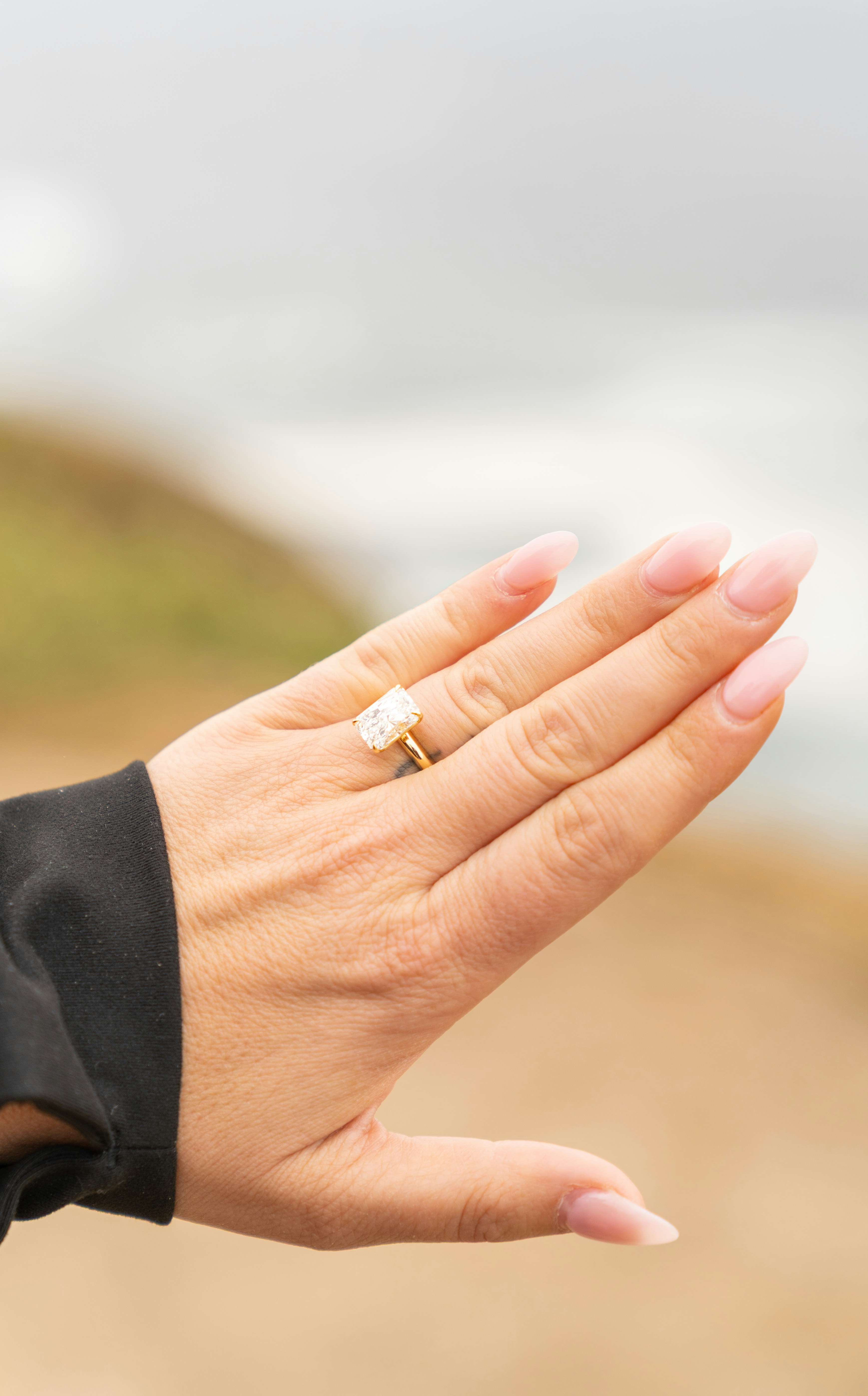 Mano mostra un grande anello ovale di diamanti con unghie rosa.