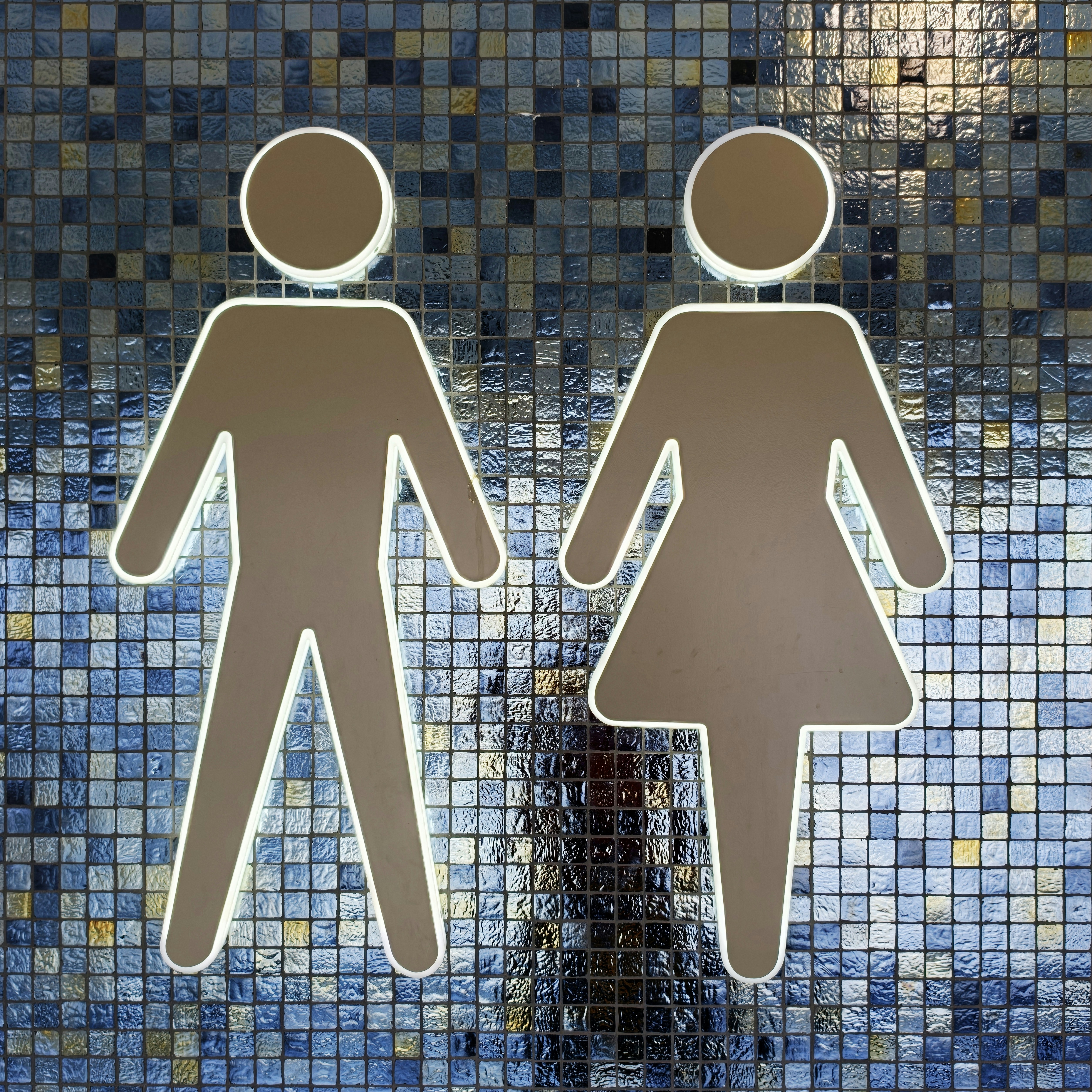 Male and female restroom symbols on a blue tiled wall.