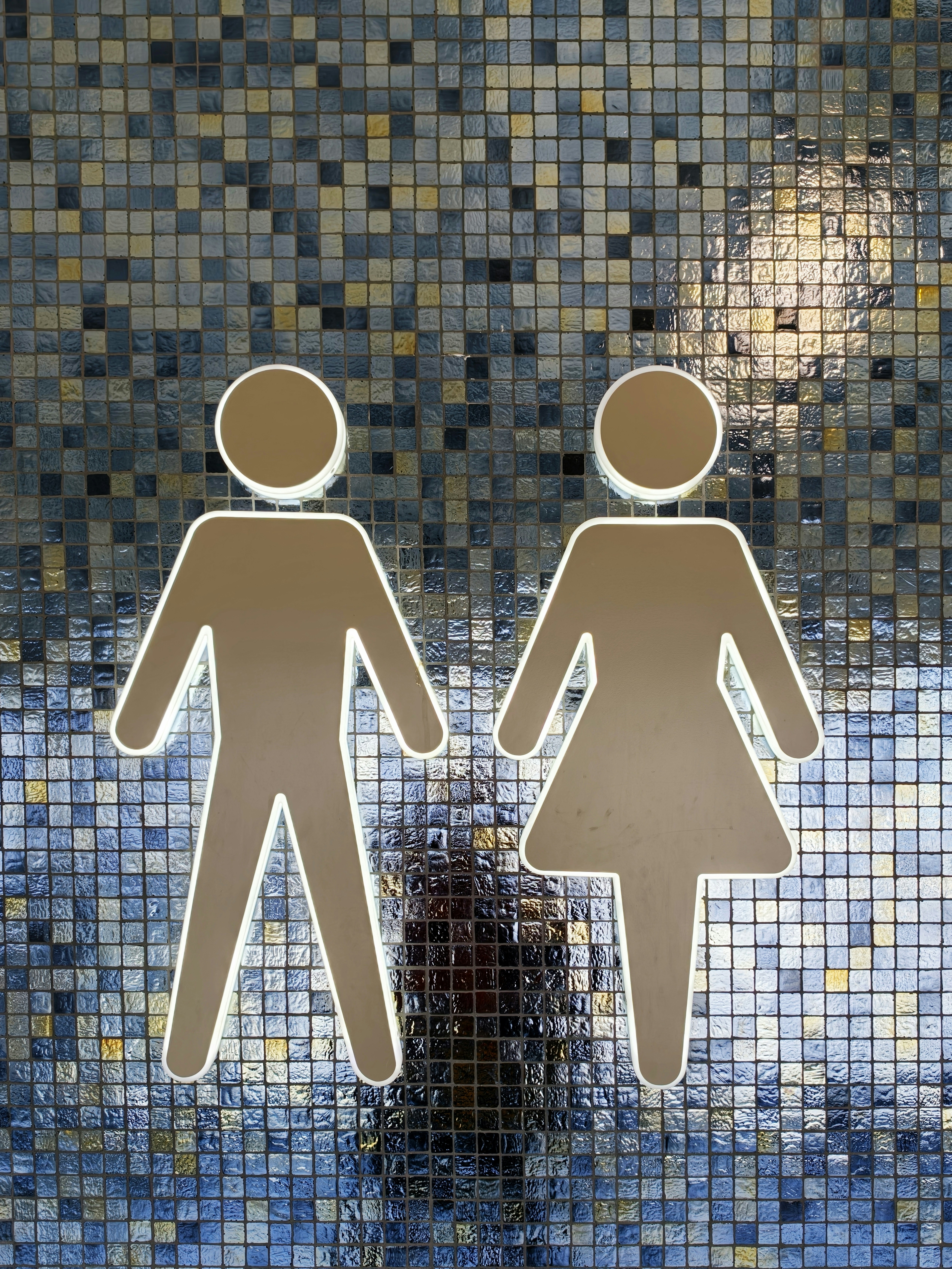 Male and female restroom symbols on a mosaic wall.