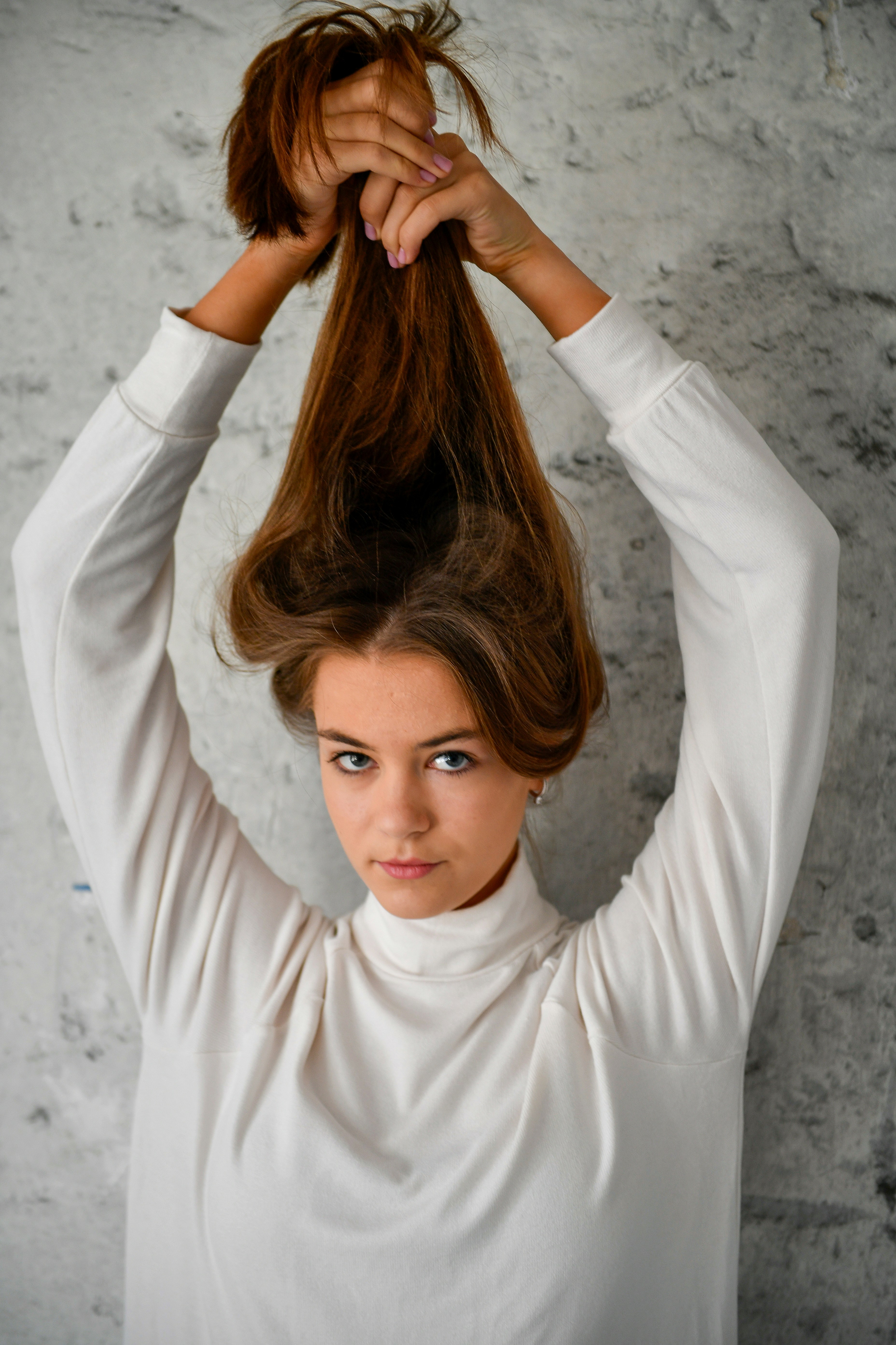 A young woman holds her long brown hair up