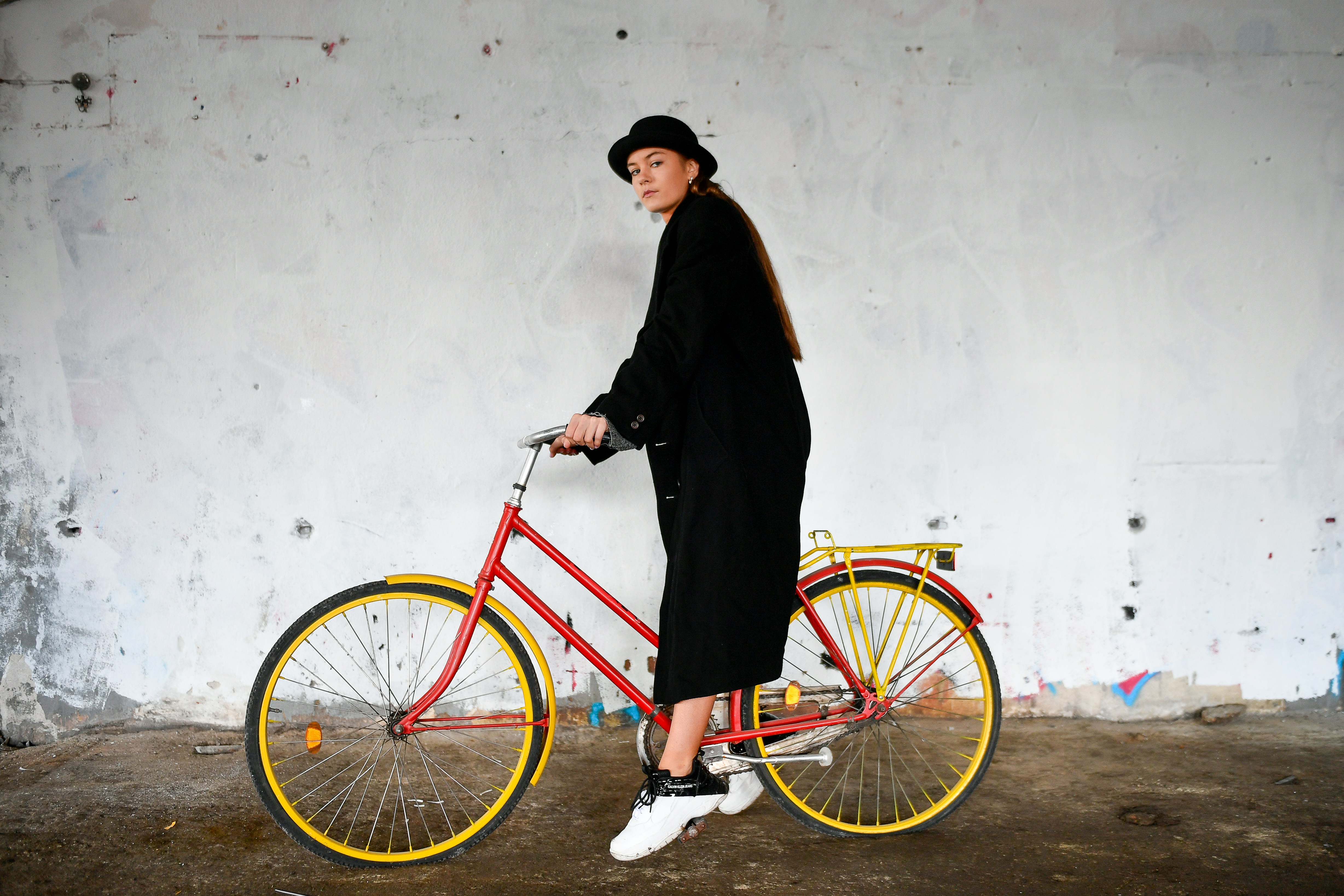 A person in black stands with a red bicycle.