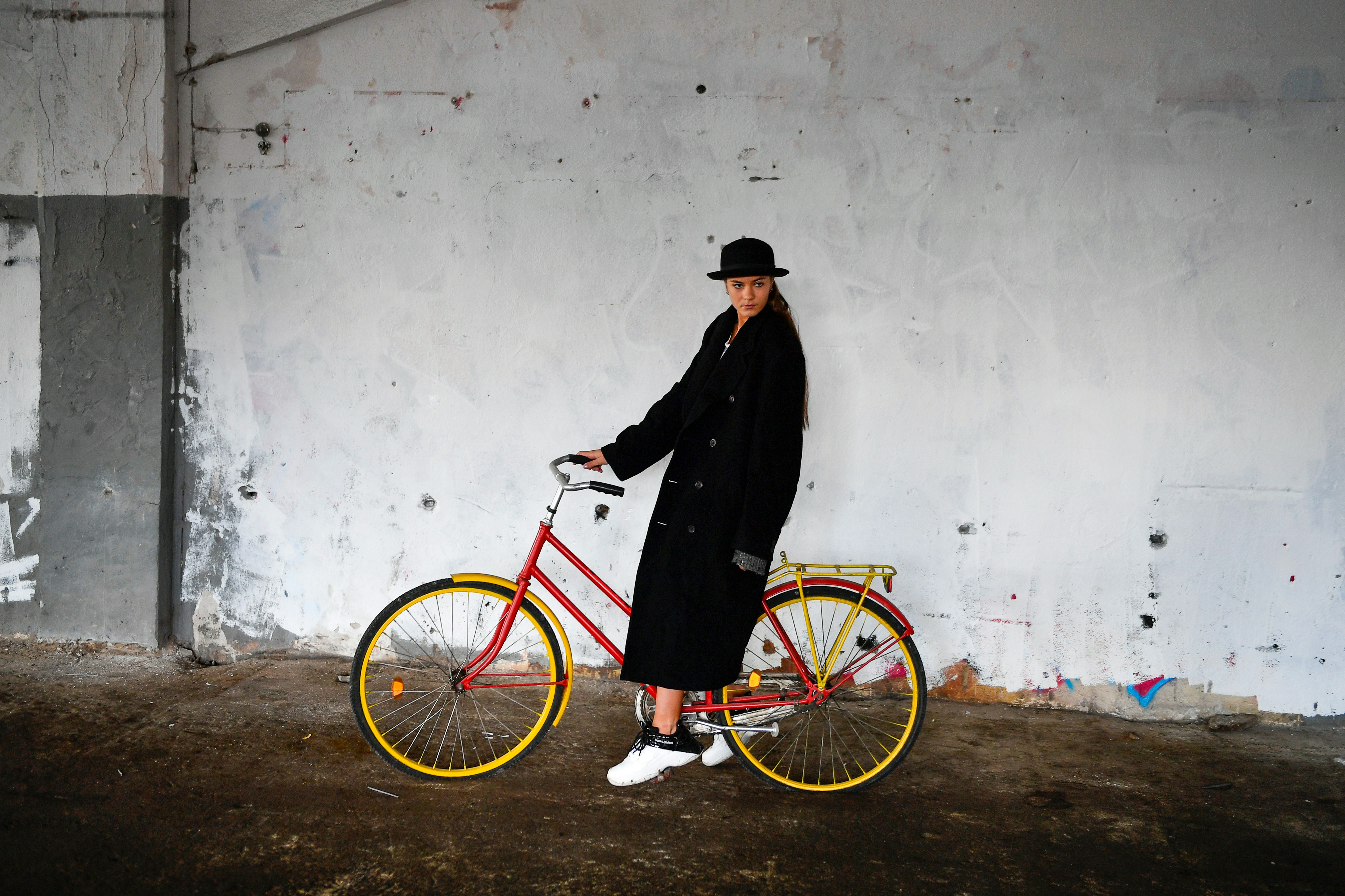Stylish woman in black coat with red bicycle.