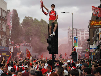 Arsenal fan celebrates on a traffic light with red smoke.
