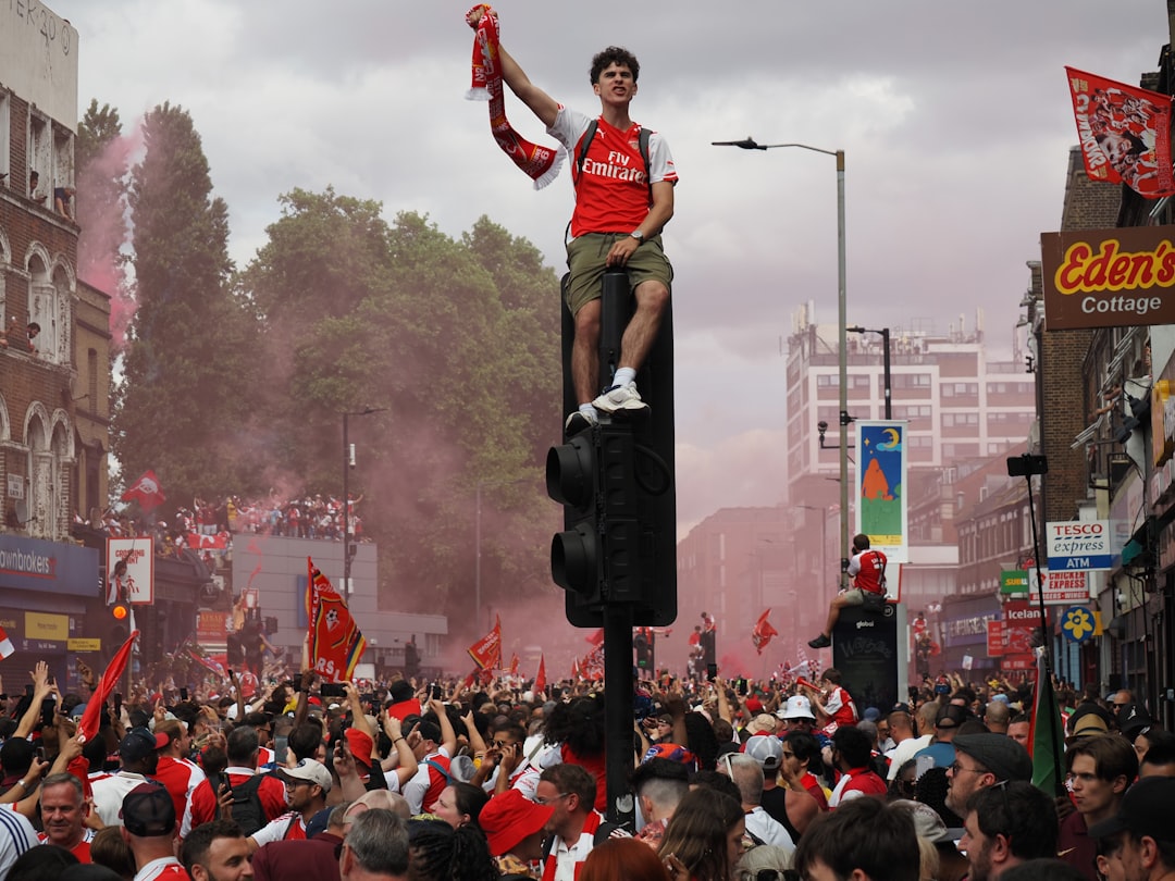 Arsenal fan celebrates on a traffic light with red smoke.