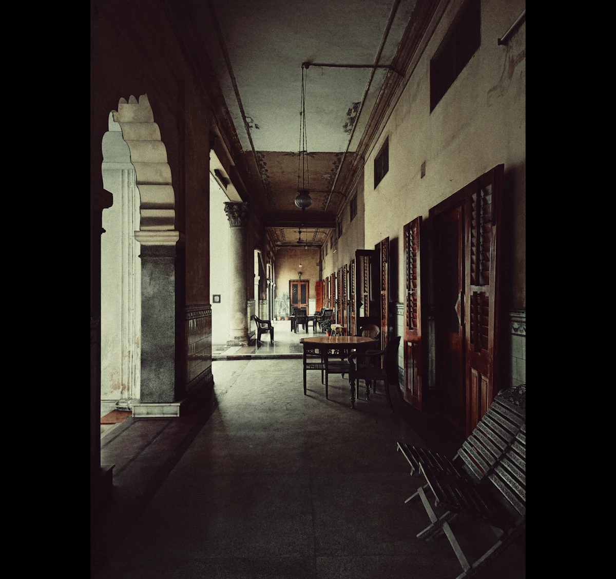 Lorong remang dengan lengkungan dan pintu kayu.