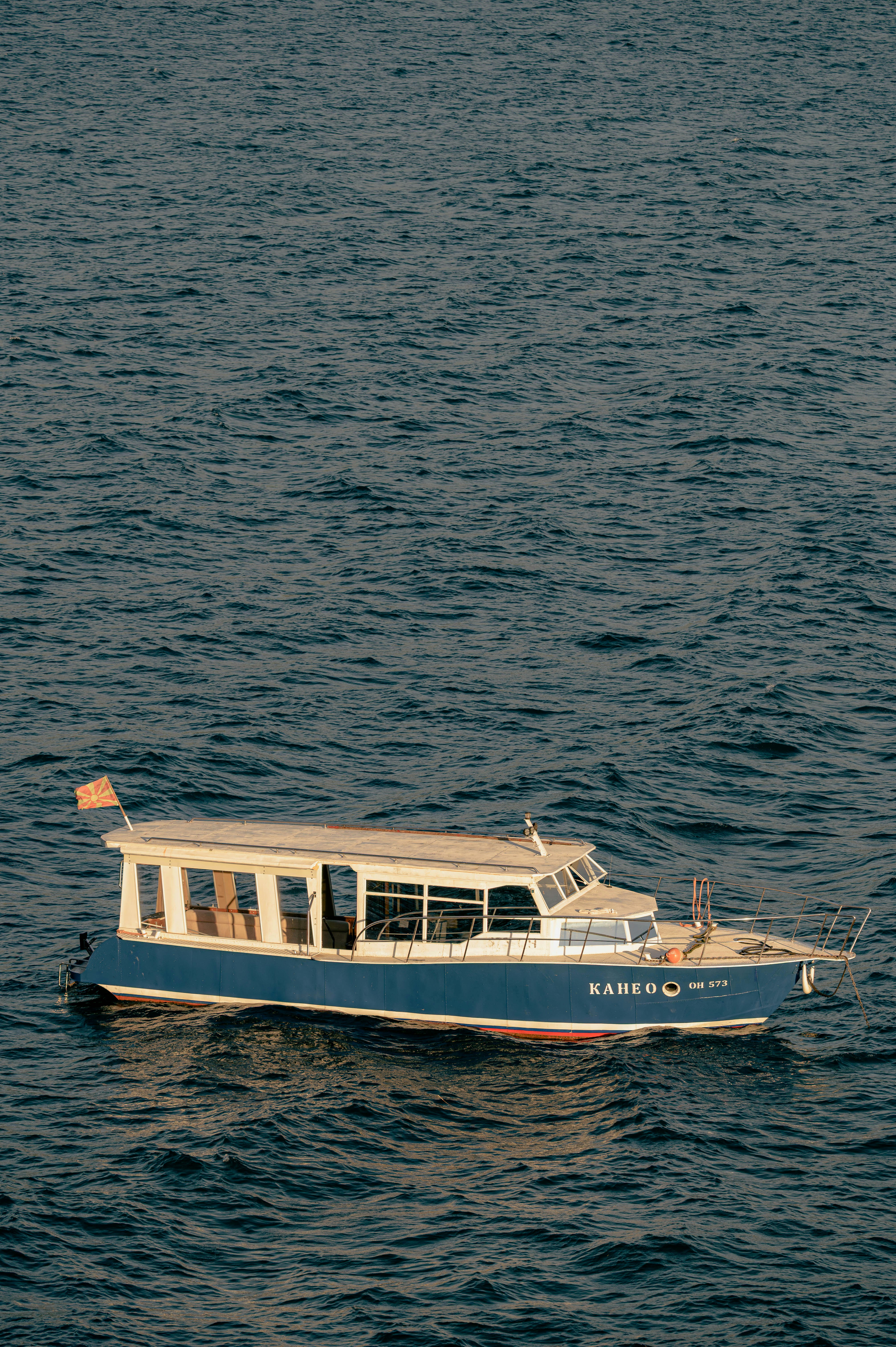 A blue and white boat floats on calm ocean water.