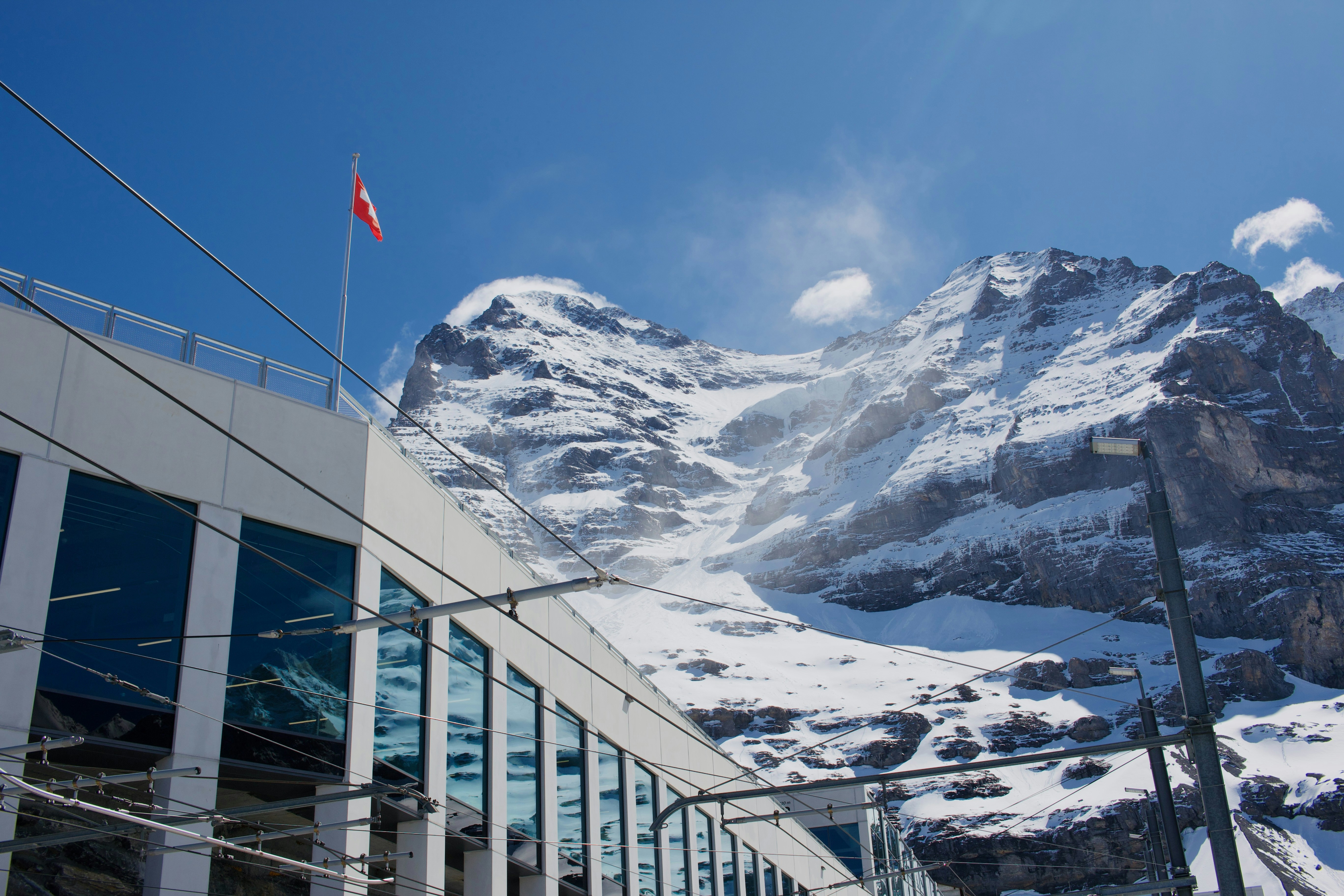 Modern building and a majestic snow-capped mountain under blue sky.