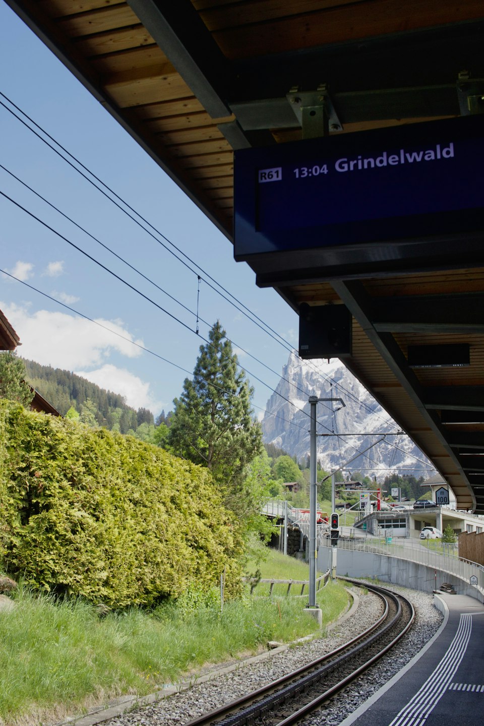 Grindelwald train station platform and tracks with snowy mountains behind