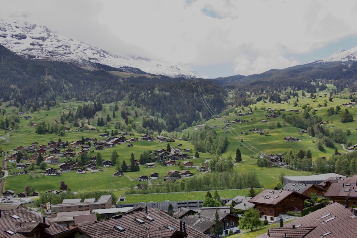 Grüne Bergwiese mit Feriendorf vor markantem Gipfel im Montafon