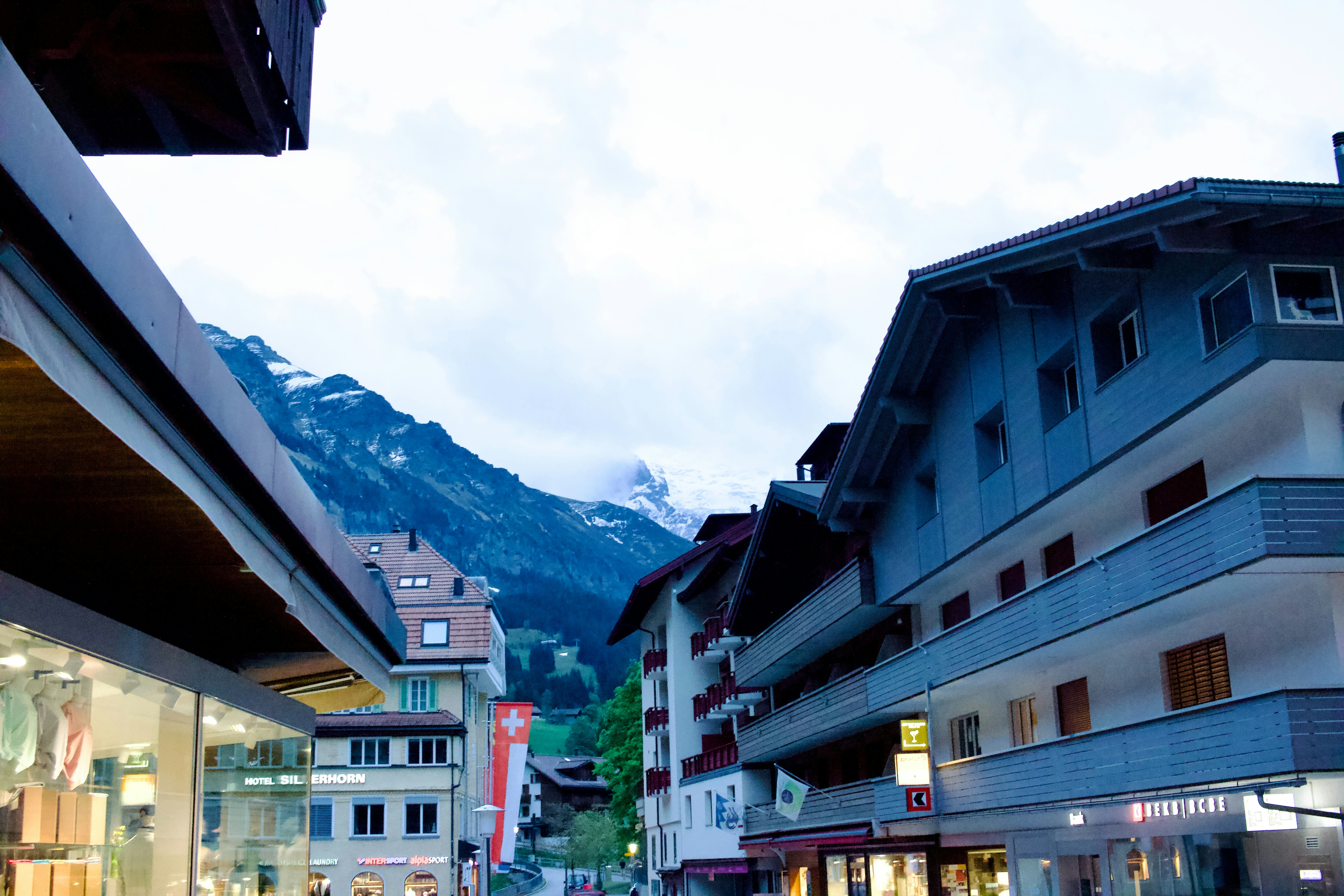 A traditional alpine village street of timber chalets below snow-capped peaks