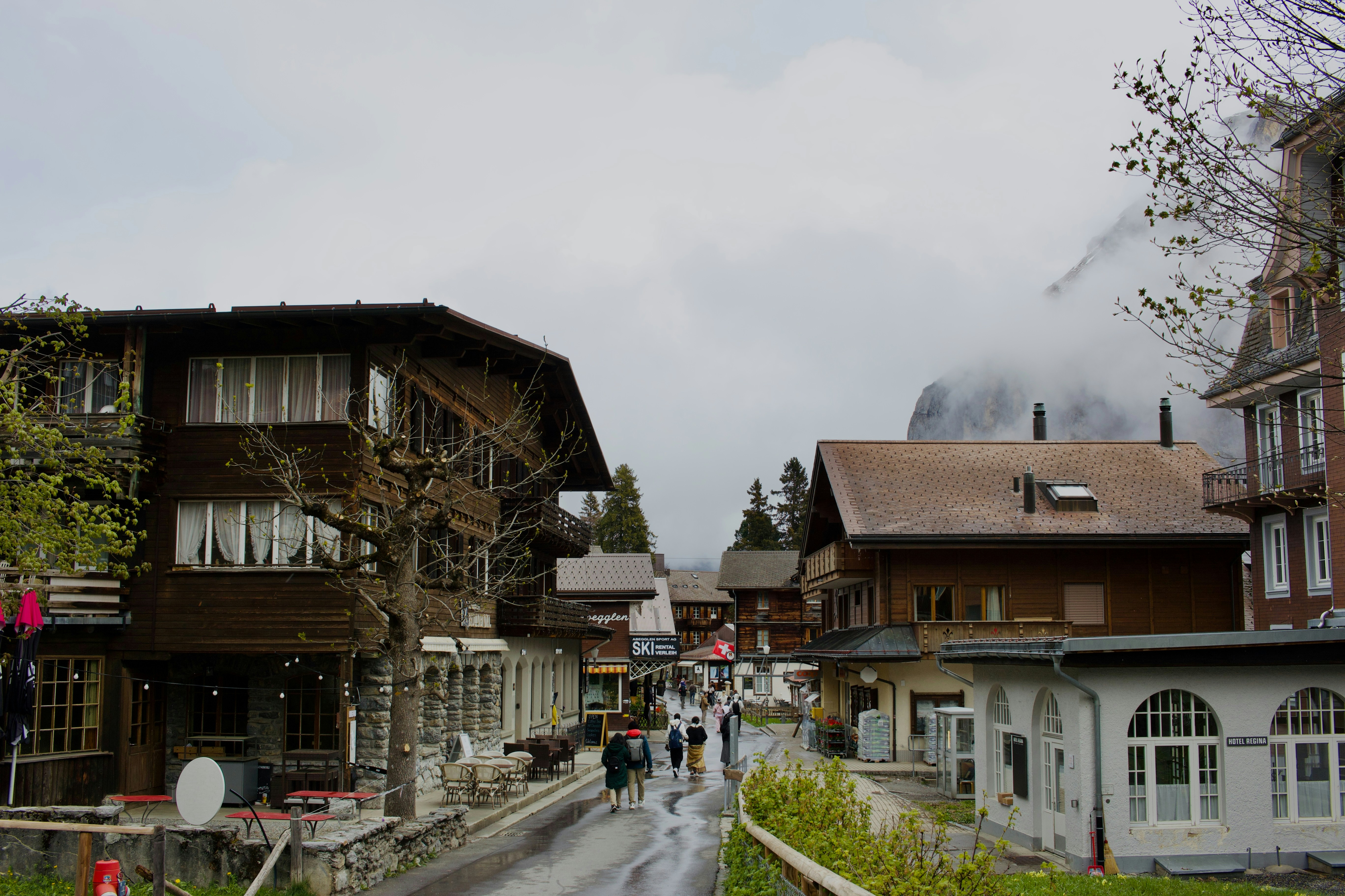 Village street with traditional wooden buildings and foggy mountains.