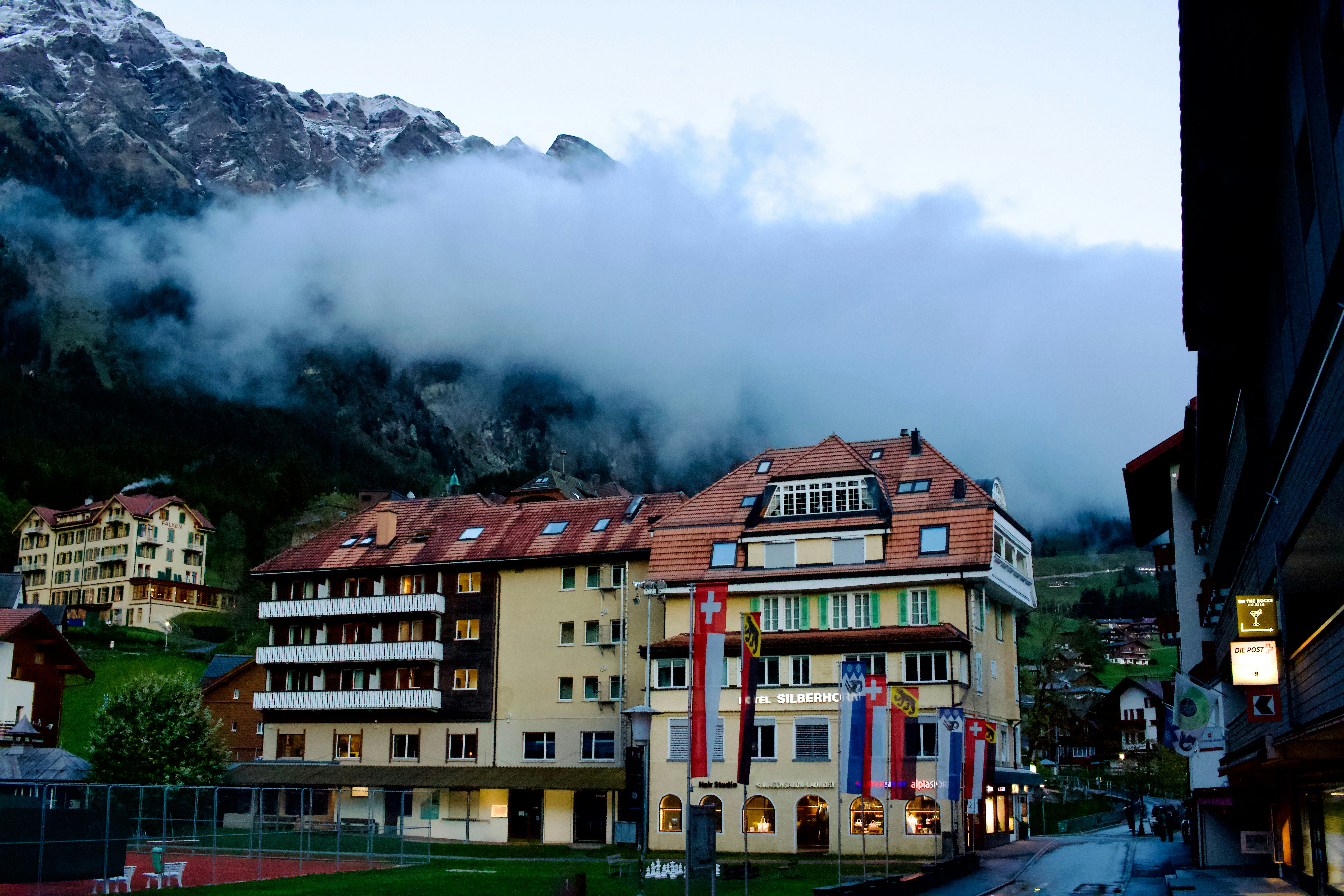Swiss hotel building nestled in a cloudy mountain valley.