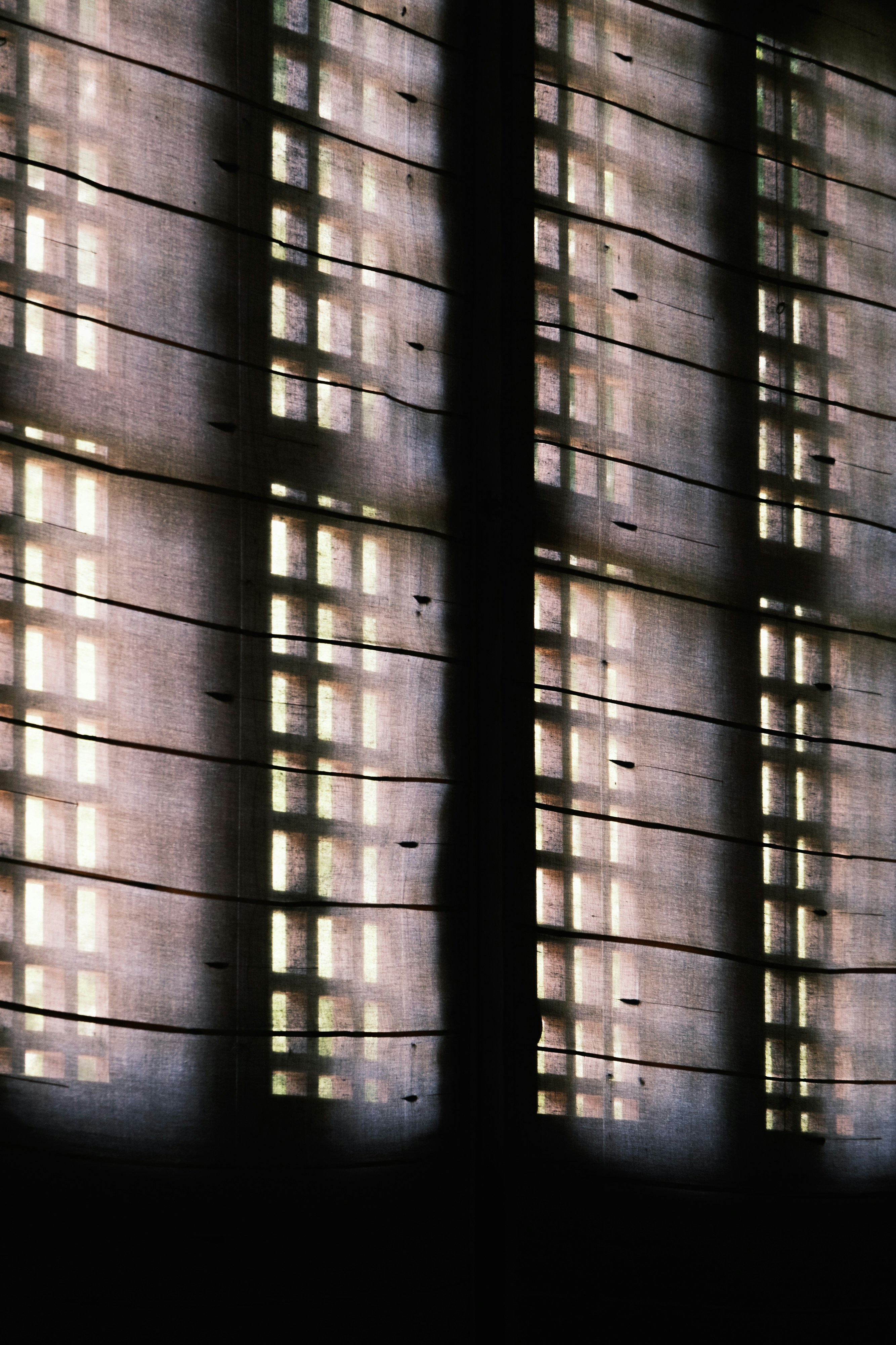 Light streams through window blinds, creating grid shadows.