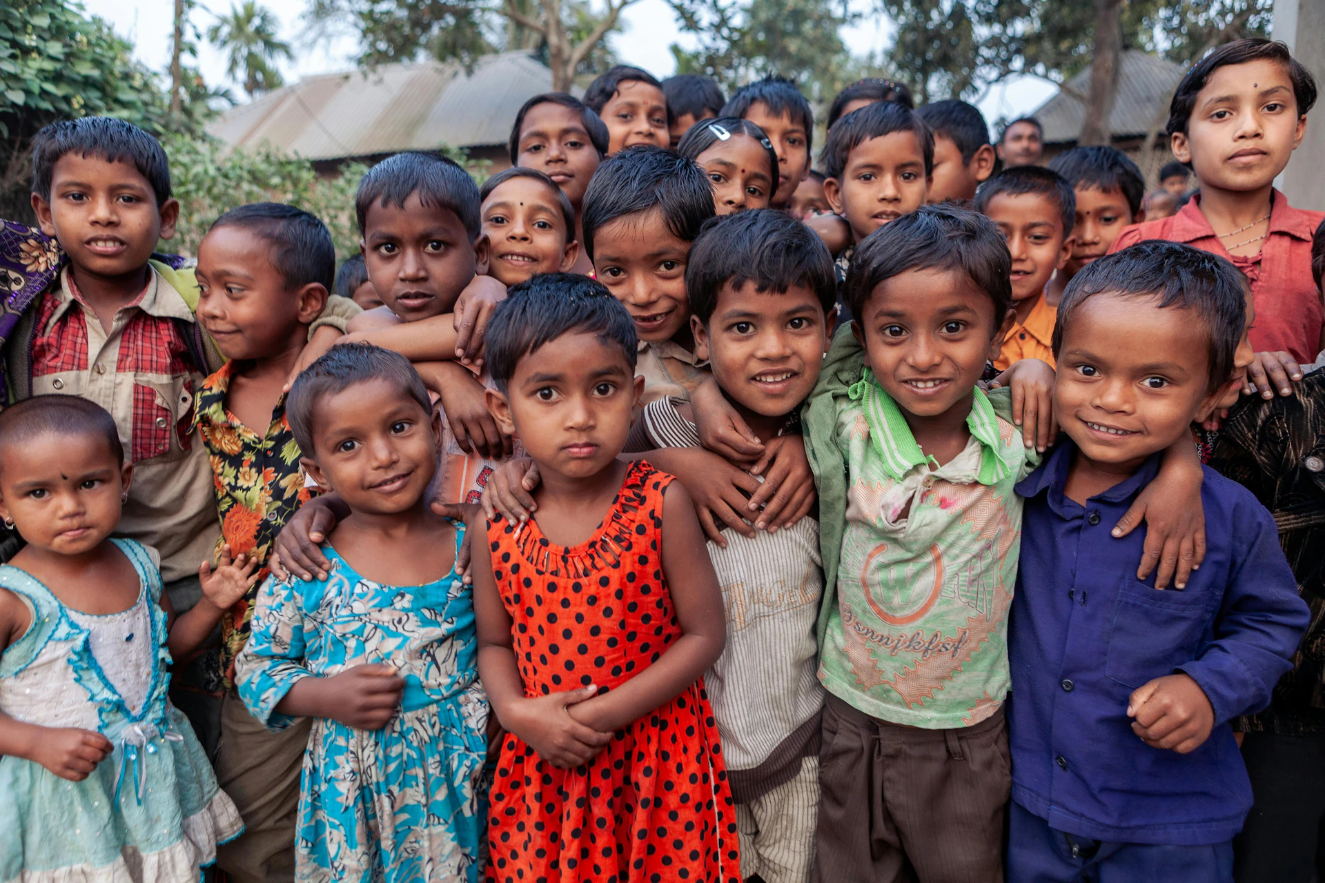 Group of smiling children standing closely together outdoors.