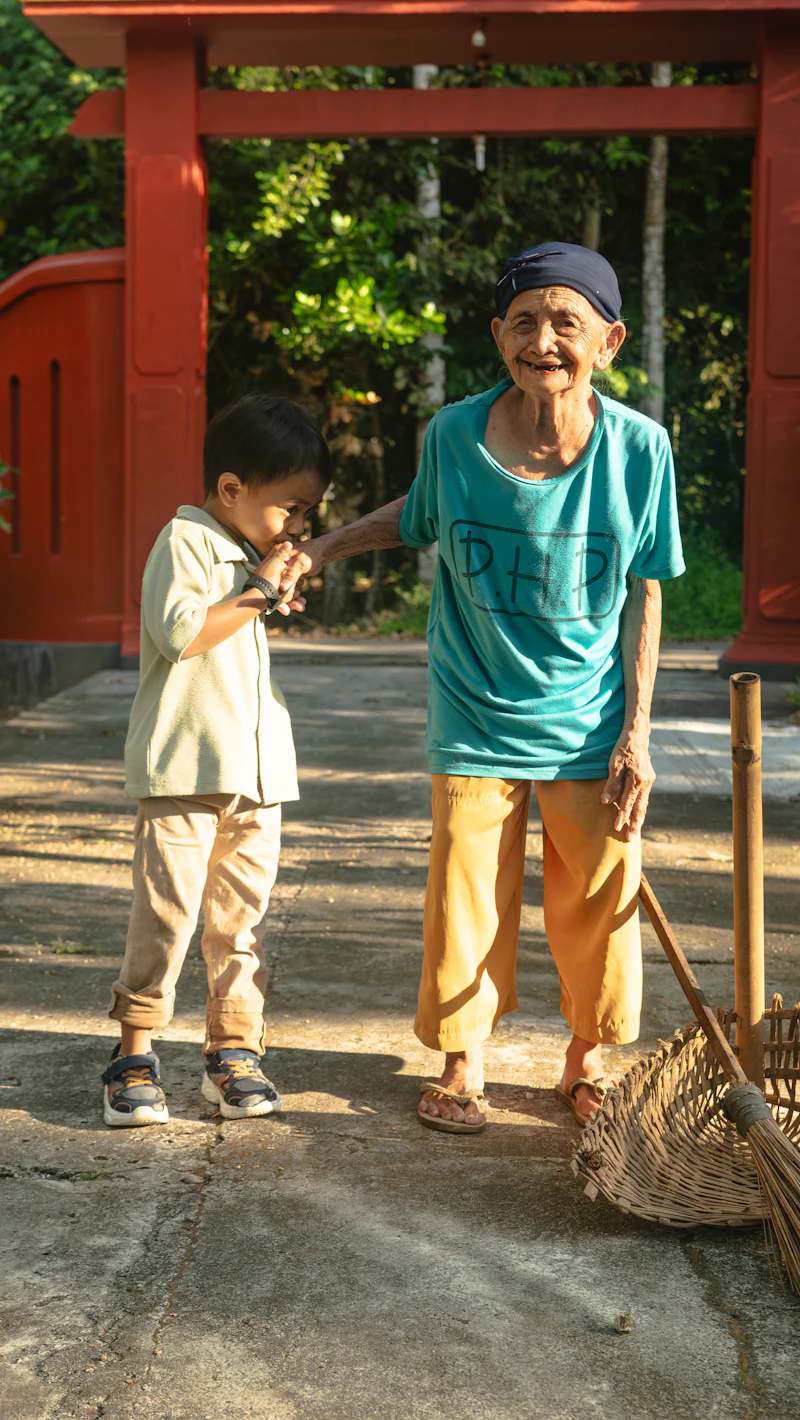 An older woman and a young boy standing outdoors together, both smiling.