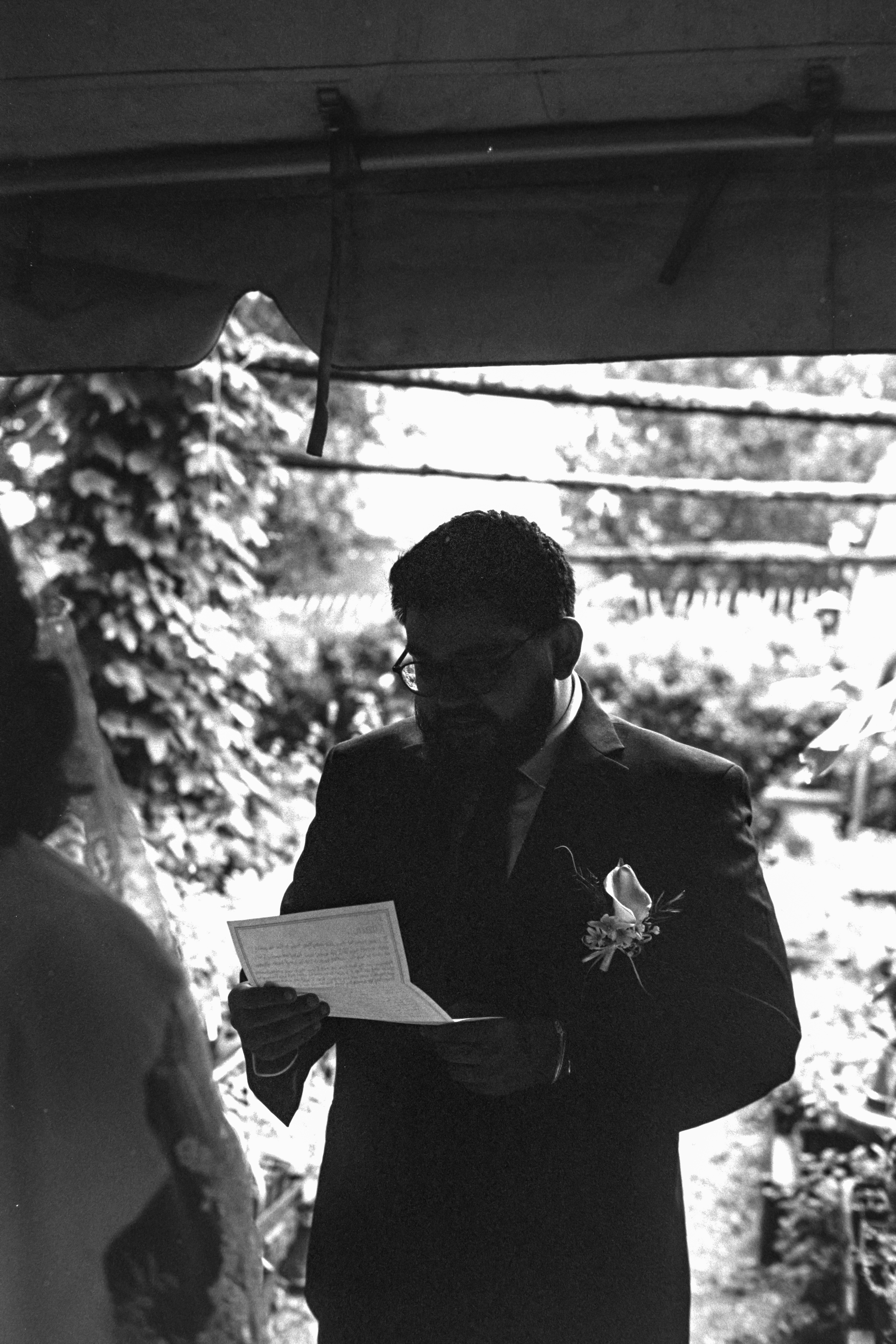 A man in a suit reads a paper outdoors