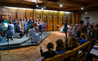 A conductor leads an orchestra performing for an attentive audience.