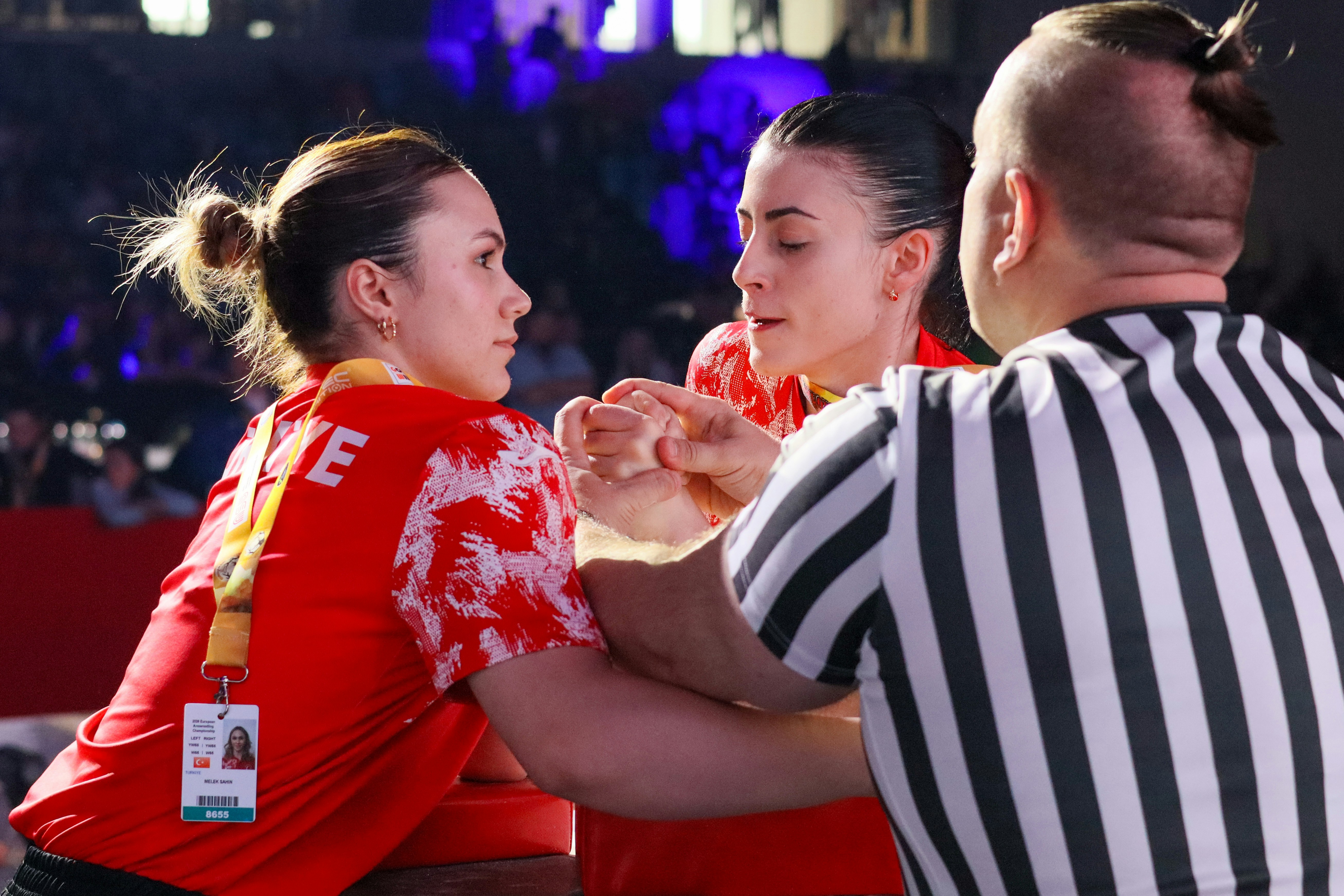 Dua wanita bergulat lengan dengan wasit yang hadir.
