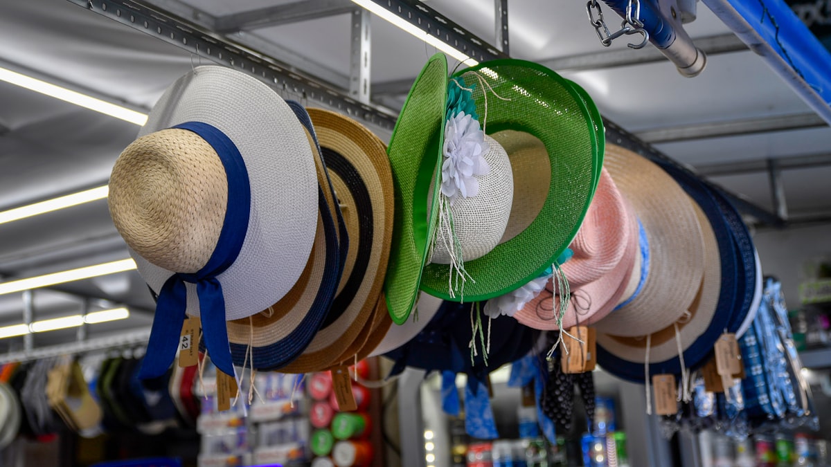 Straw sun hats hanging in a row at an outdoor market