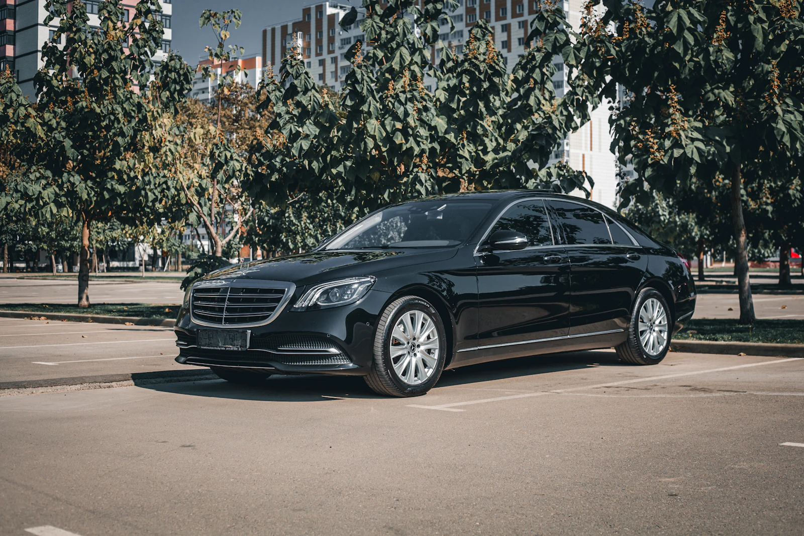 Gloss-black Mercedes-Benz S-Class sedan parked beneath autumn trees