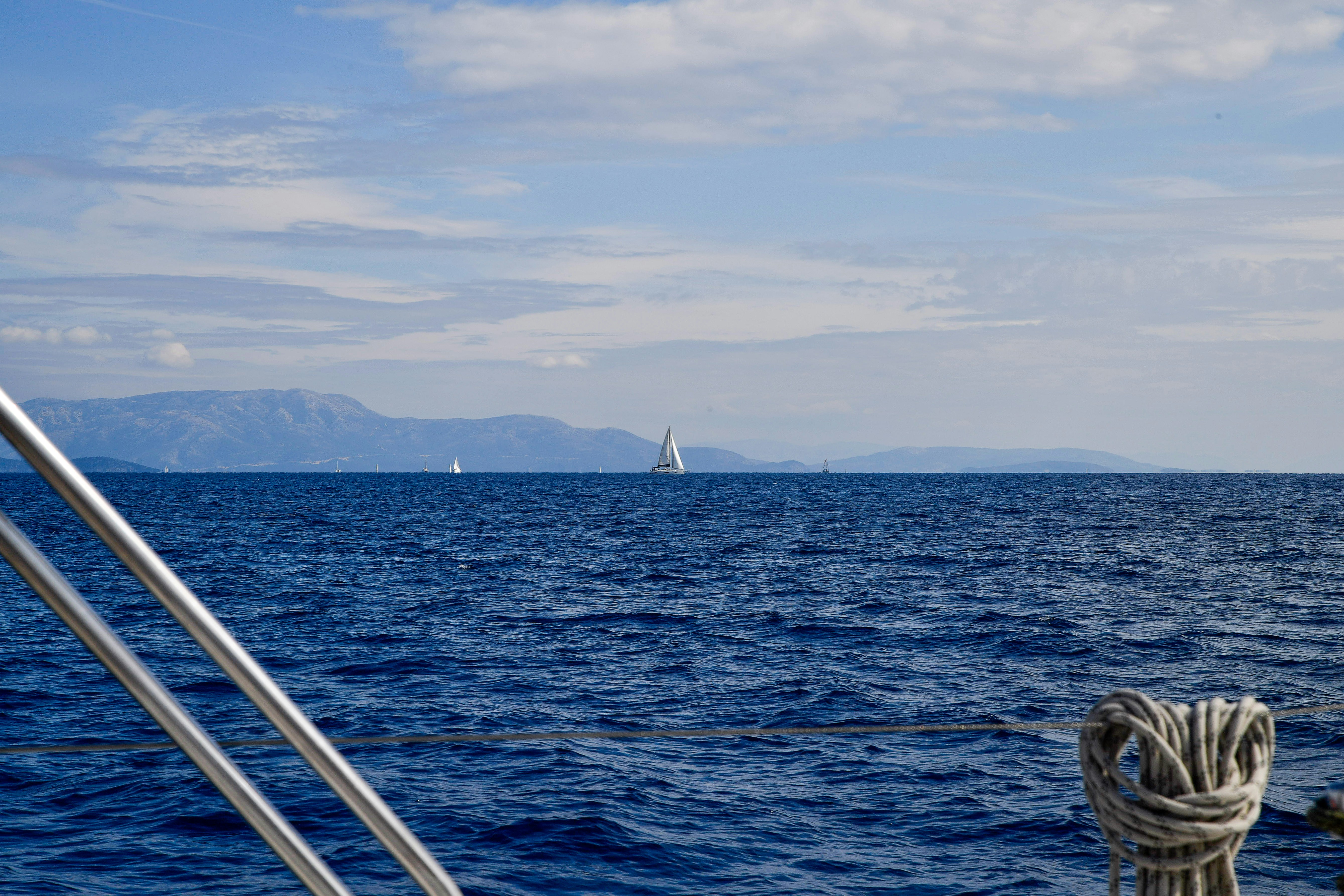 Sailboats on a vast blue ocean with distant mountains