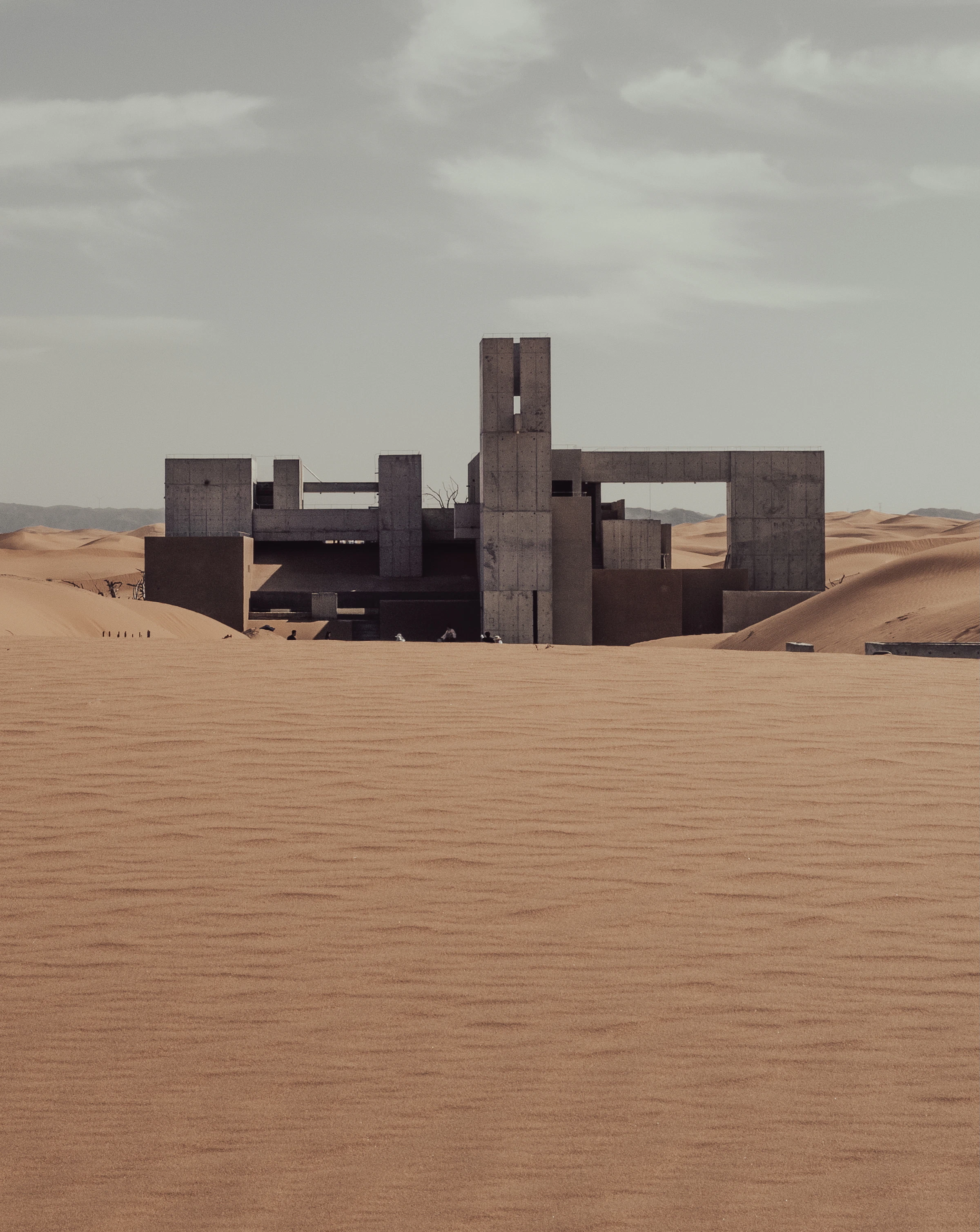 Monumental concrete structure surrounded by desert sand