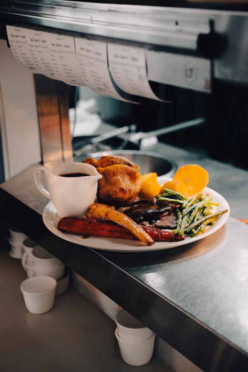 A Sunday roast with Yorkshire pudding and a jug of gravy waiting on the pass