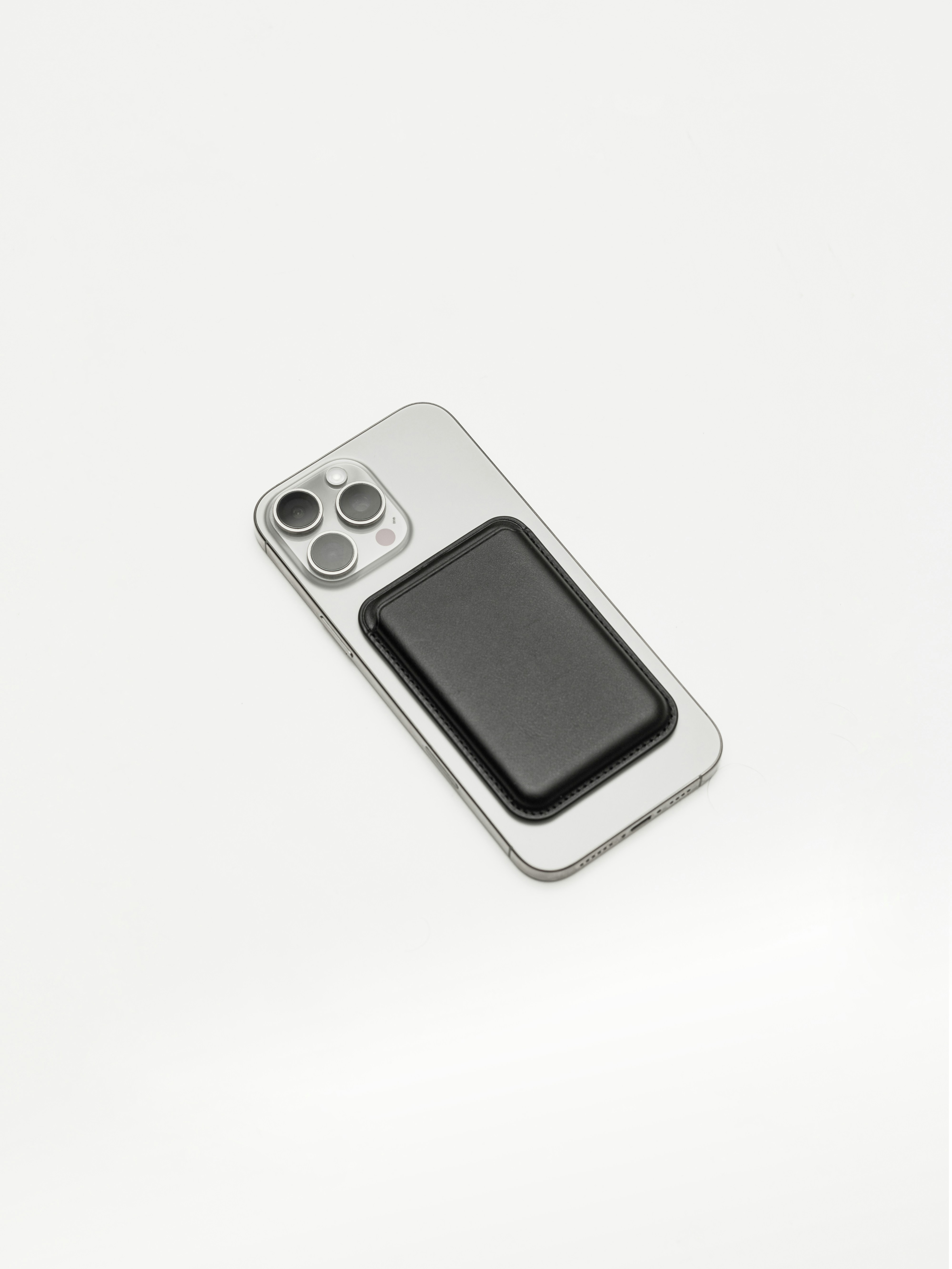 Silver smartphone with black magnetic wallet on a white background.