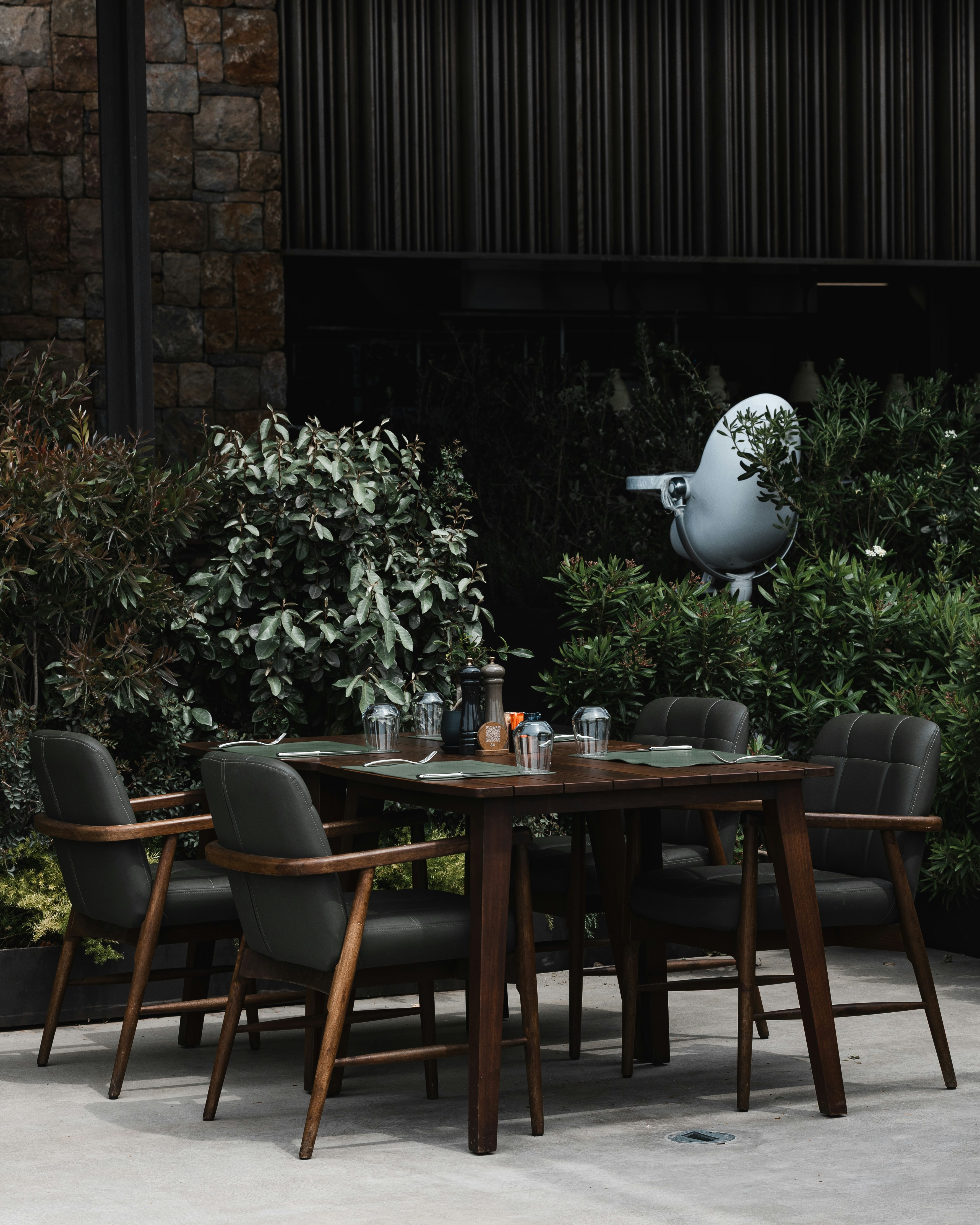 Outdoor dining table and chairs surrounded by lush greenery.