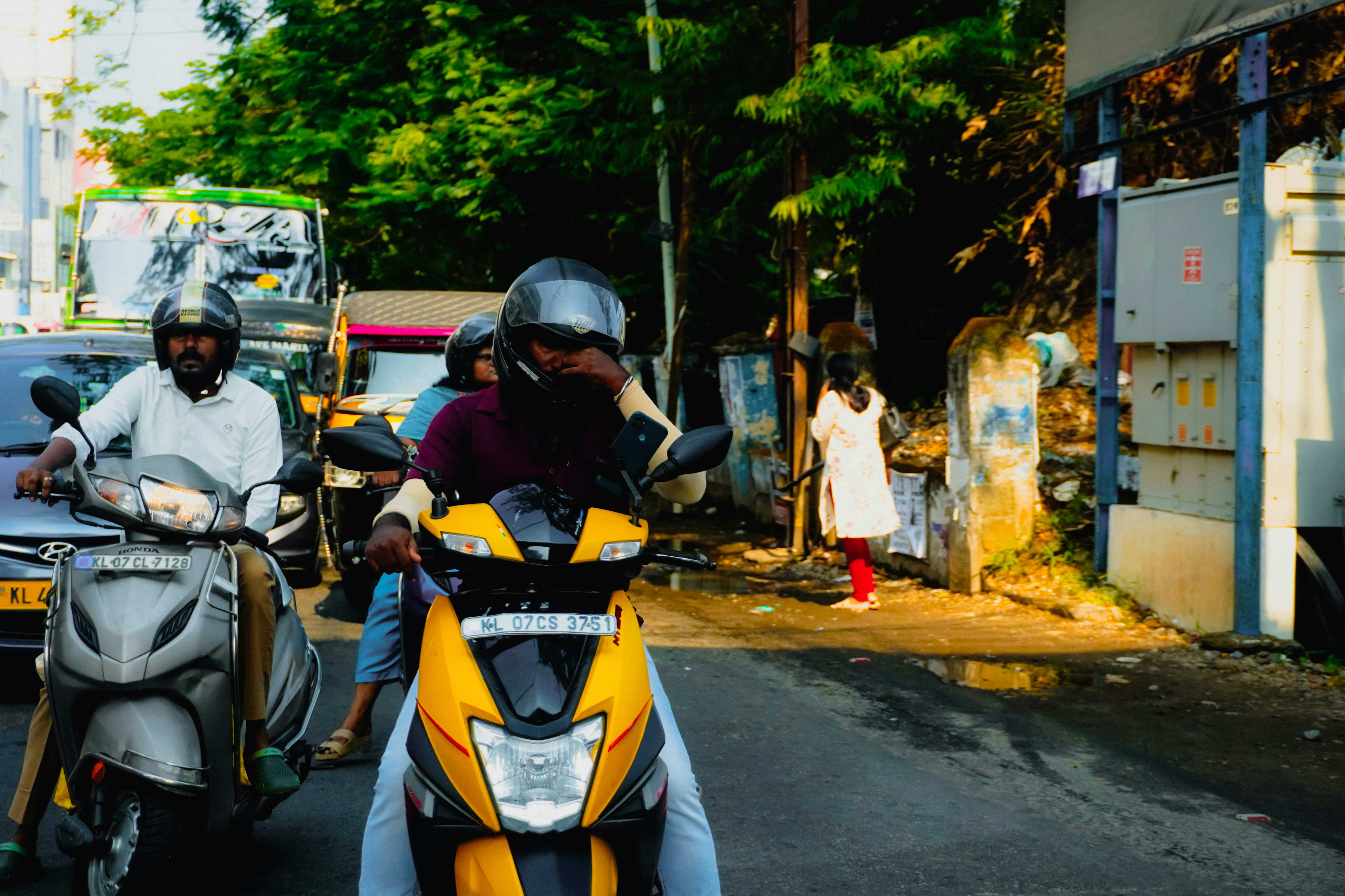 Orang-orang mengendarai skuter di jalan yang sibuk.