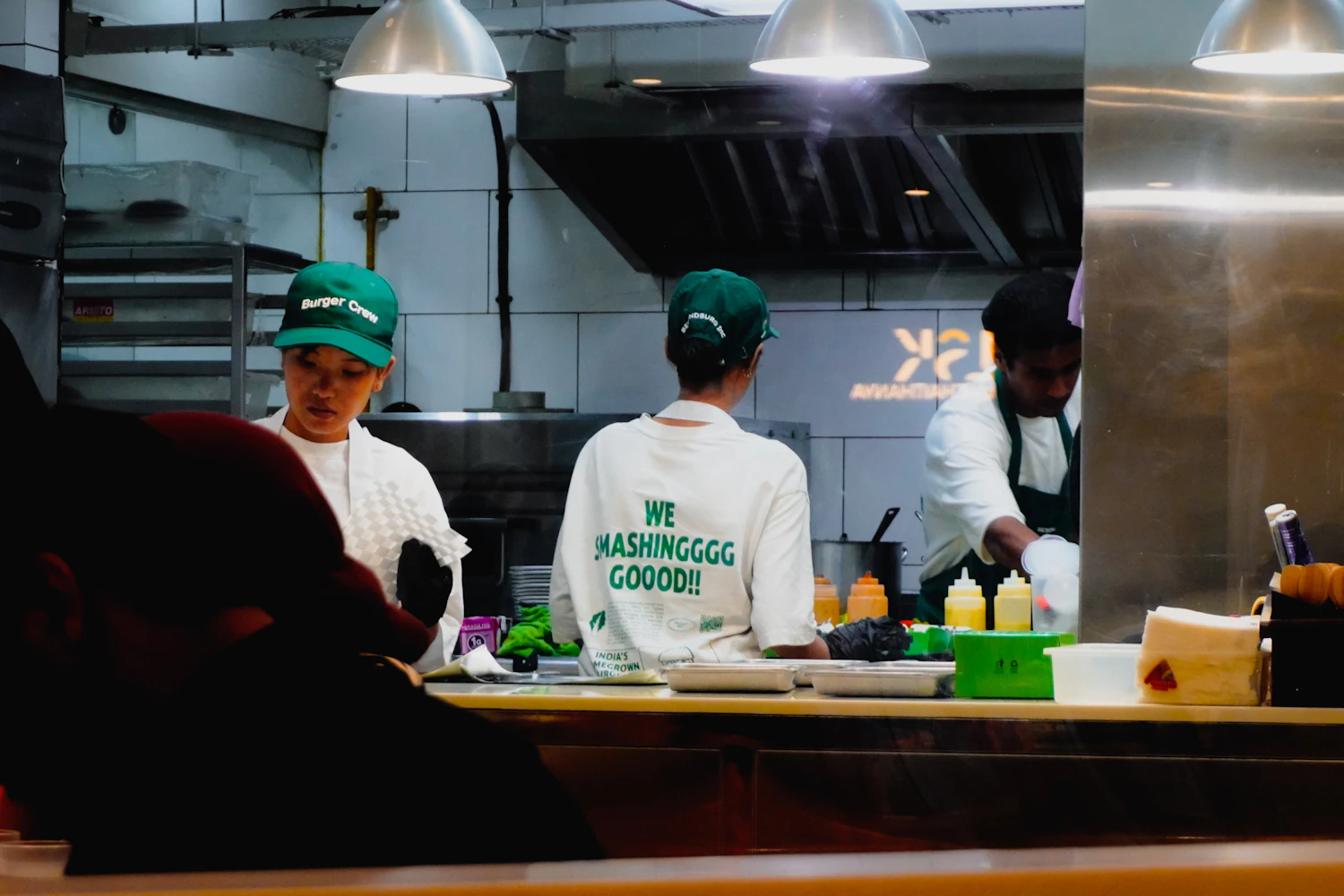 Restaurant staff prepare food behind the counter in a professional kitchen.