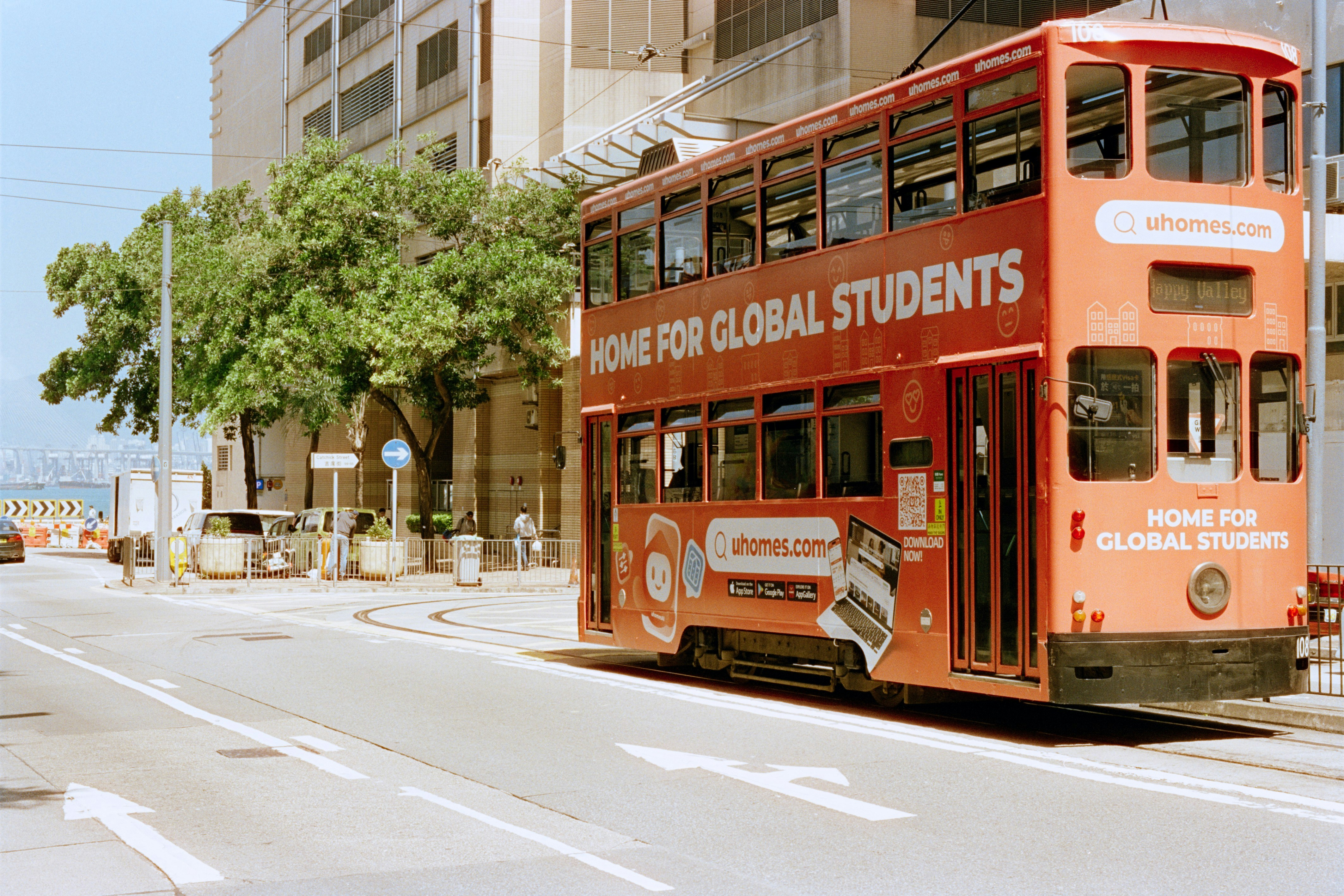 A red double-decker tram on a city street.