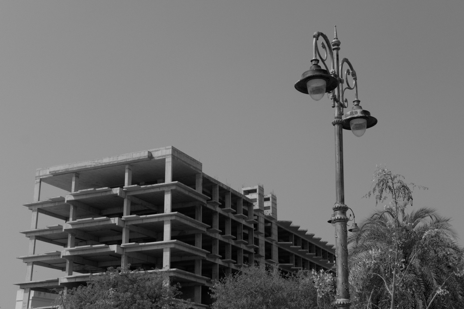 Ornate street lamp stands before an unfinished building structure.