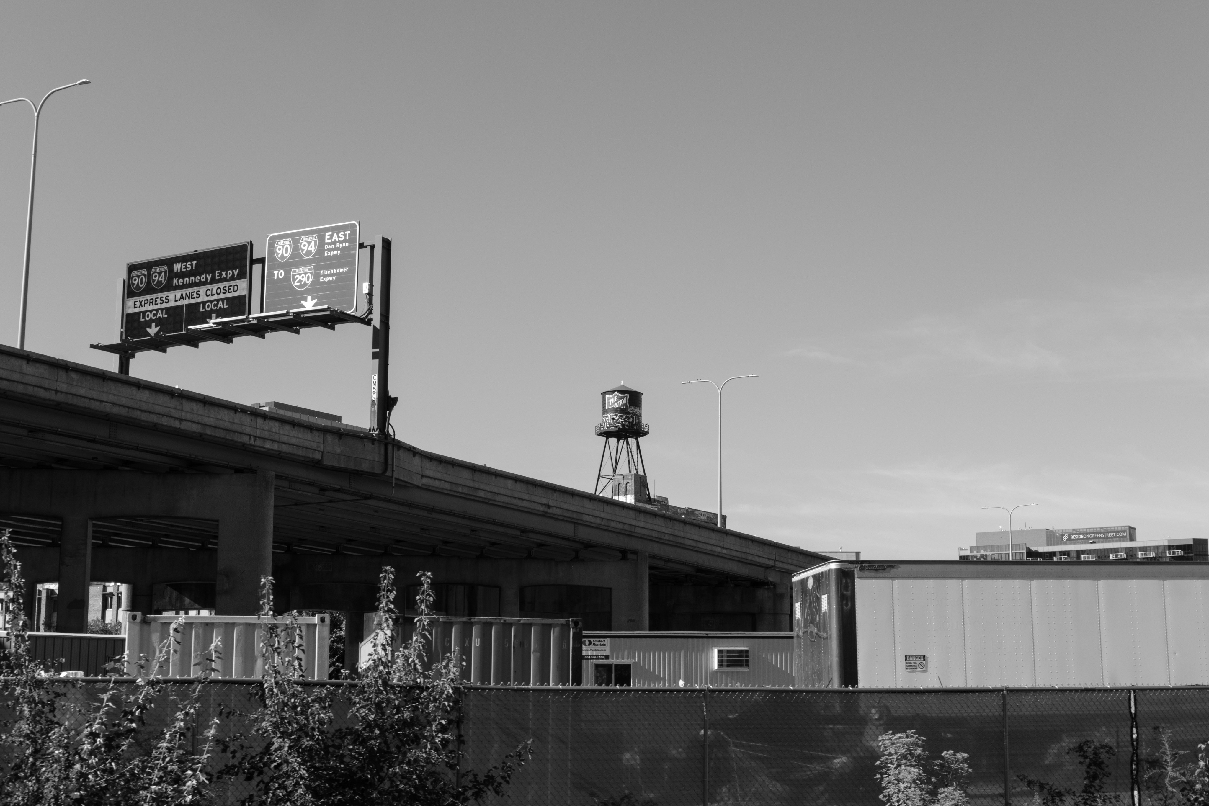 Urban landscape with billboard, elevated structure, and distant water tower.